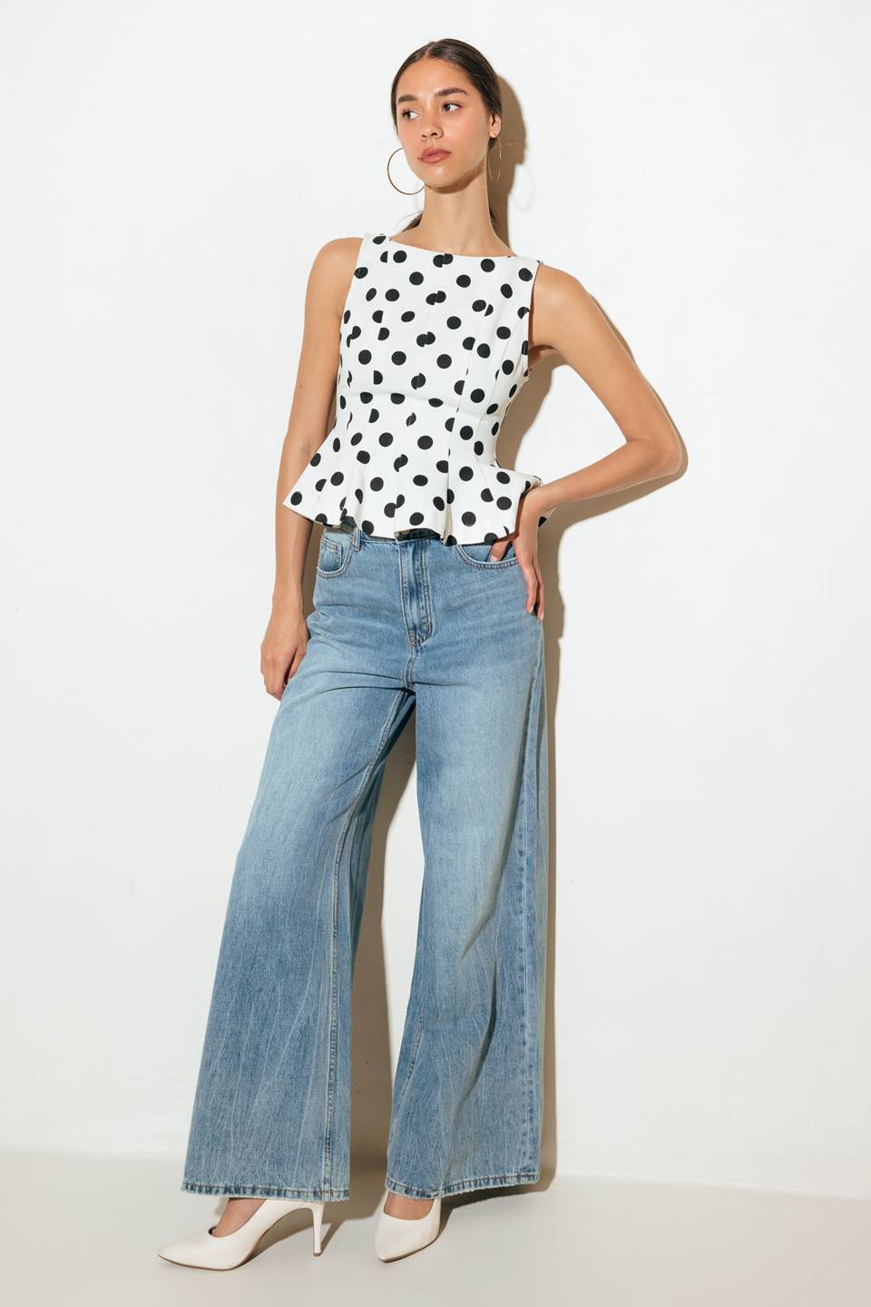 A white, polka-dotted printed woven top featuring wide neckline, peplum, V back and zipper closure.