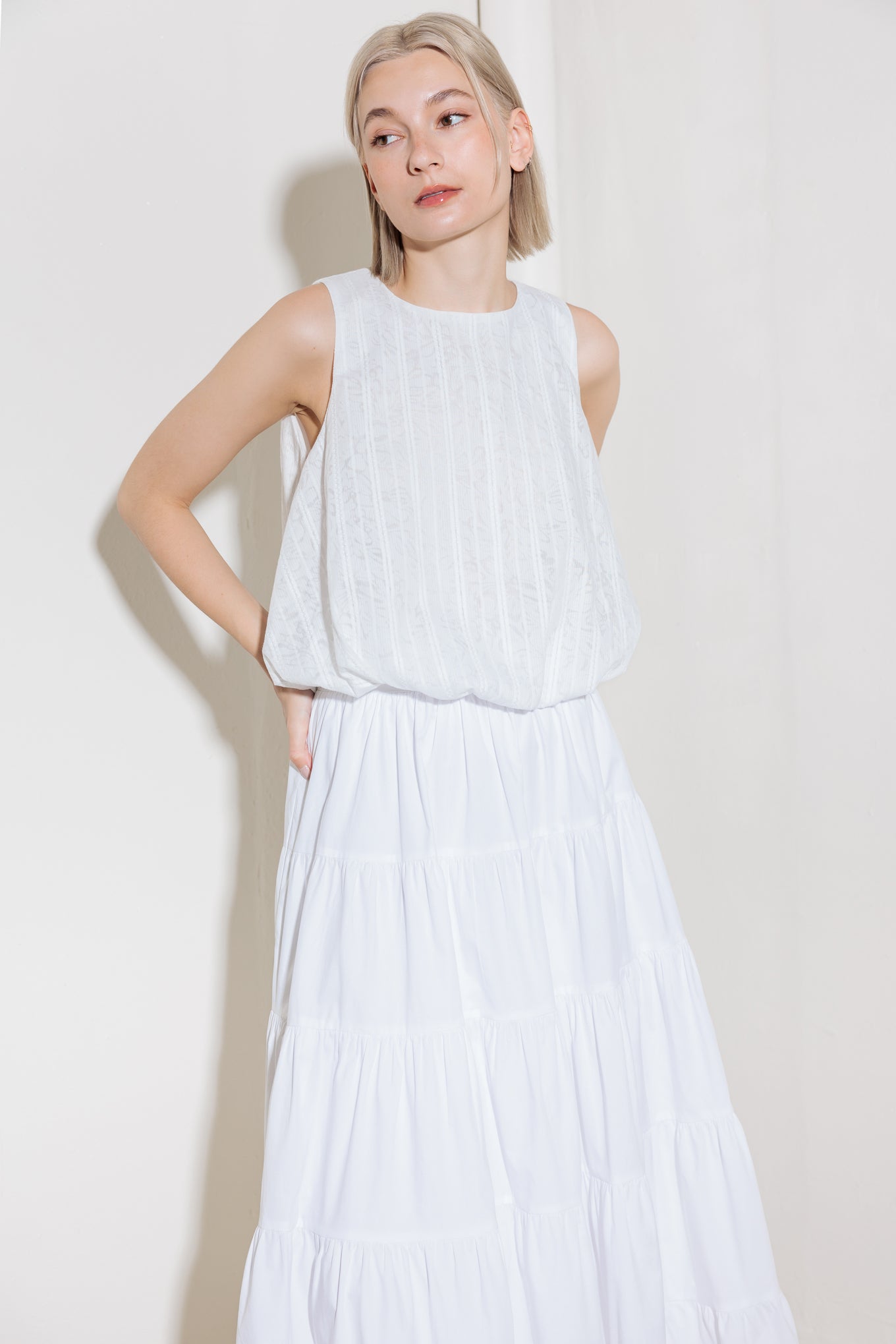 A woven lace top featuring round neckline, sleeveless and bubble hemline.