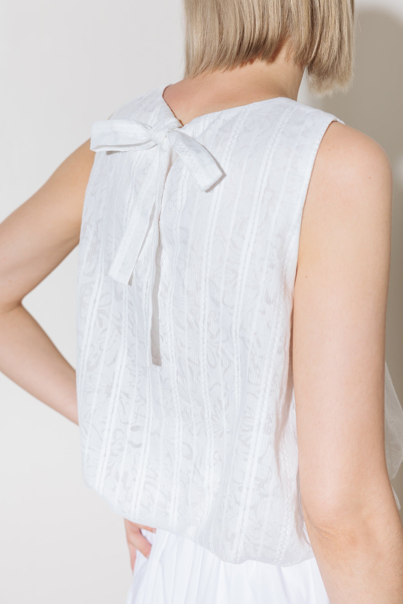 A woven lace top featuring round neckline, sleeveless and bubble hemline.