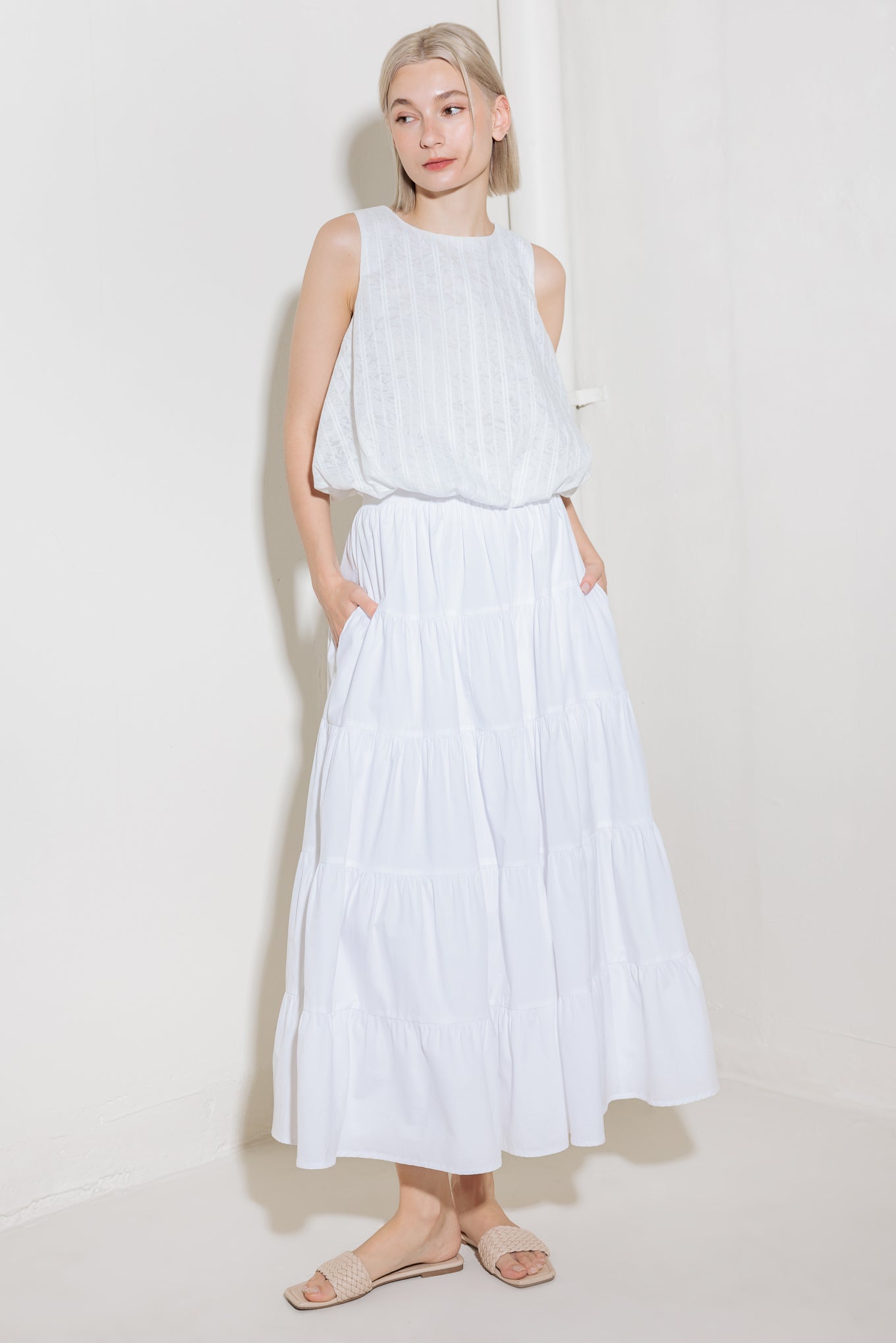 A woven lace top featuring round neckline, sleeveless and bubble hemline.