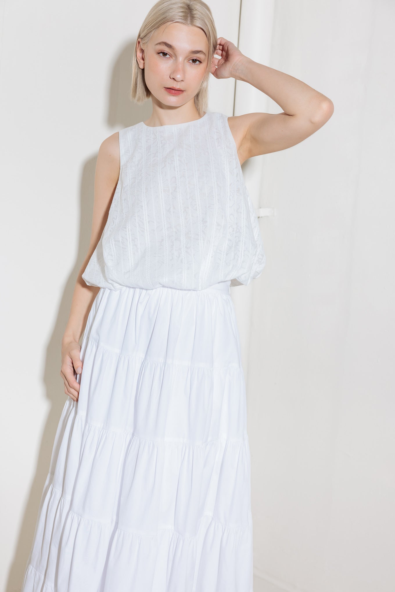 A woven lace top featuring round neckline, sleeveless and bubble hemline.