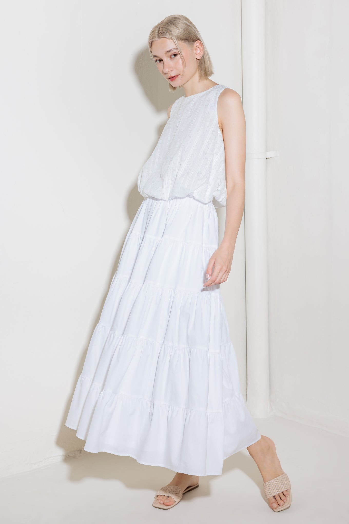 A woven lace top featuring round neckline, sleeveless and bubble hemline.