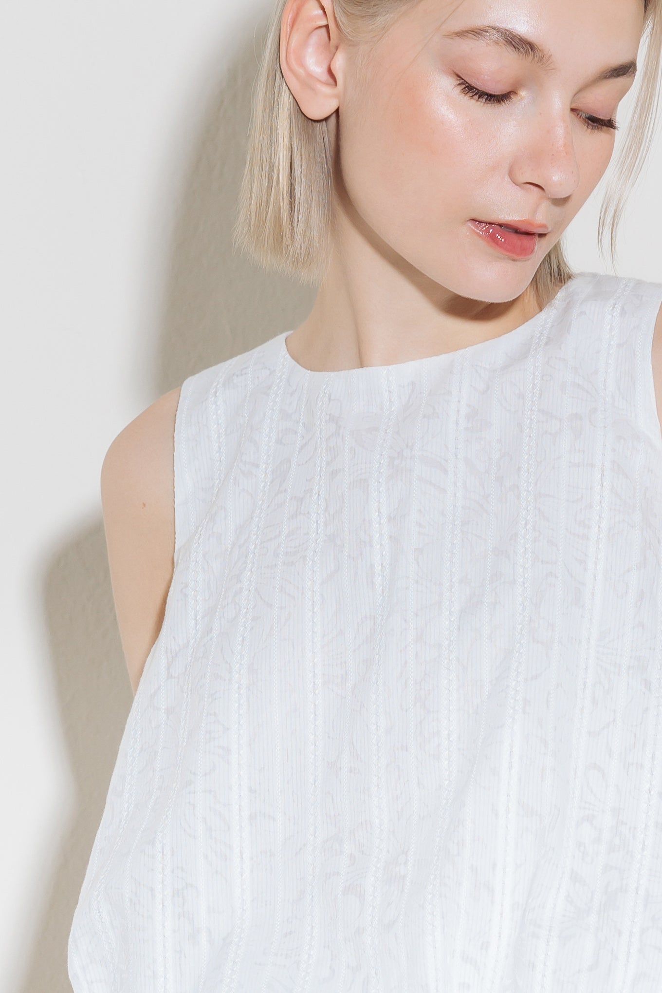 A woven lace top featuring round neckline, sleeveless and bubble hemline.