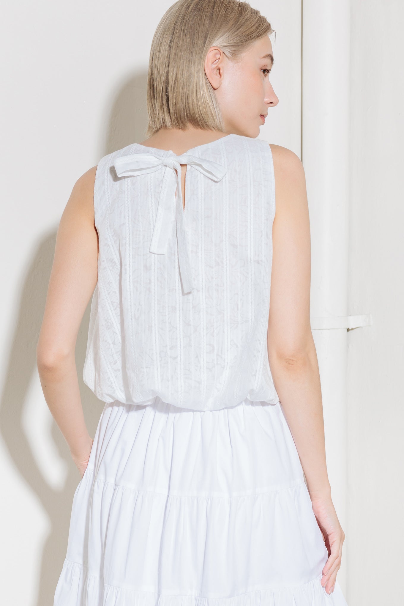 A woven lace top featuring round neckline, sleeveless and bubble hemline.