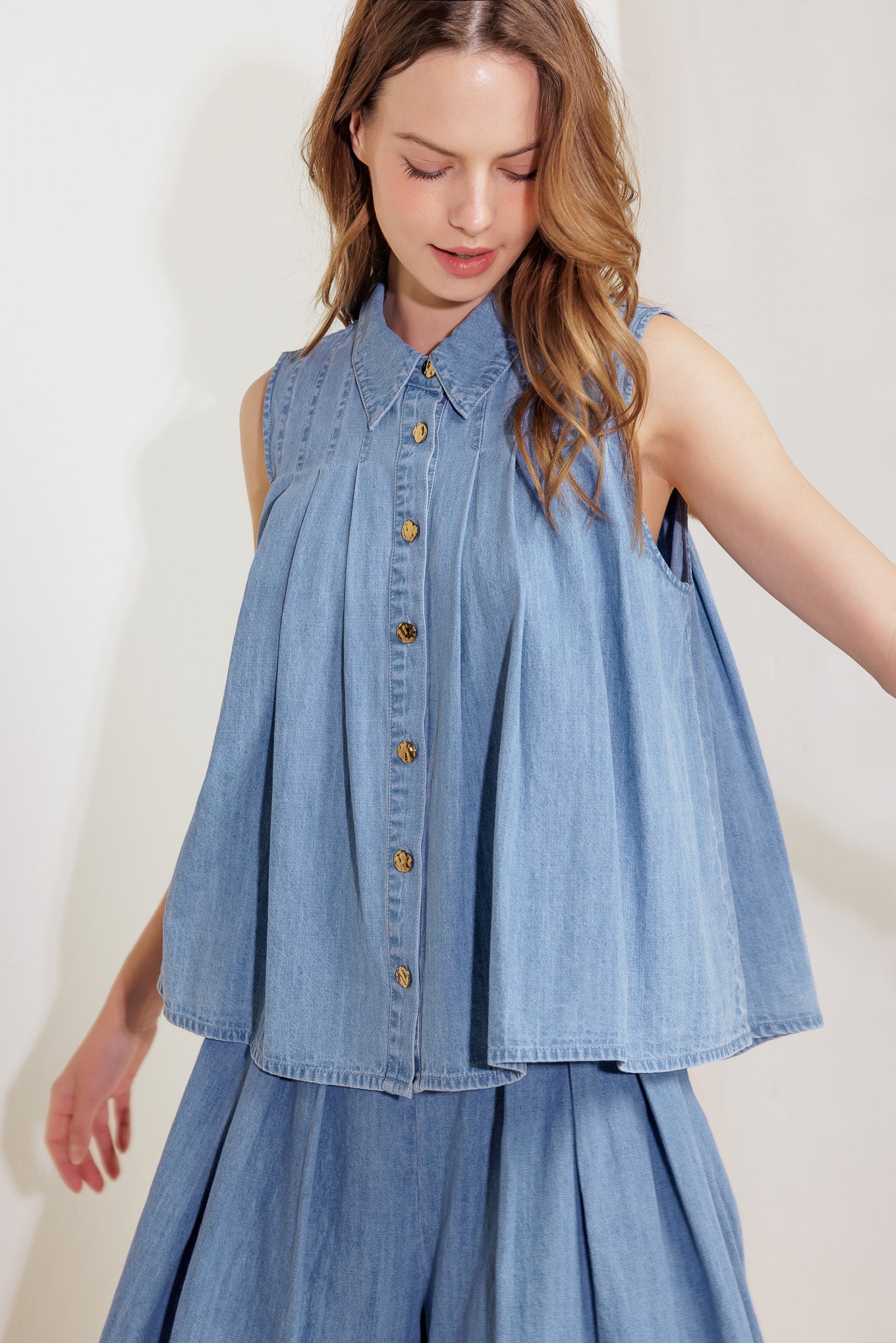 A washed chambray to featuring collar, button down, sleeveless and pleats.