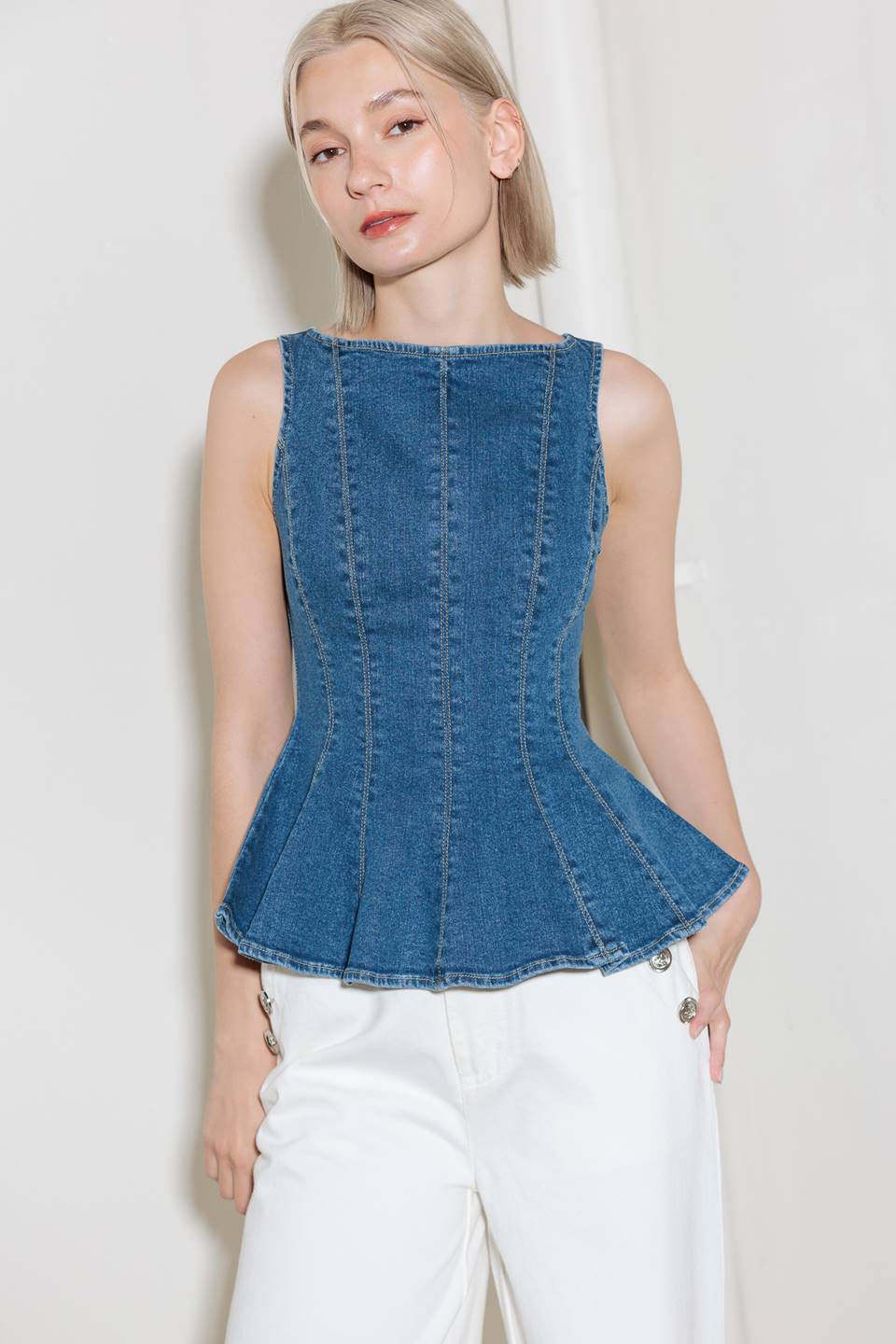 A washed denim top featuring wide neckline, sleeveless, peplum and back zipper closure.