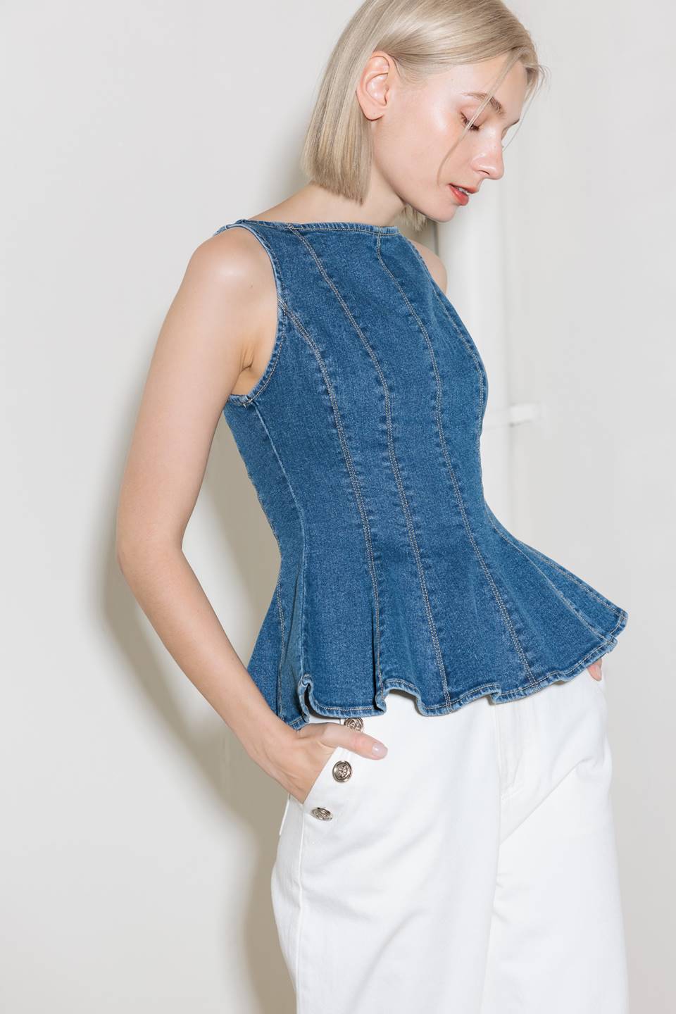 A washed denim top featuring wide neckline, sleeveless, peplum and back zipper closure.