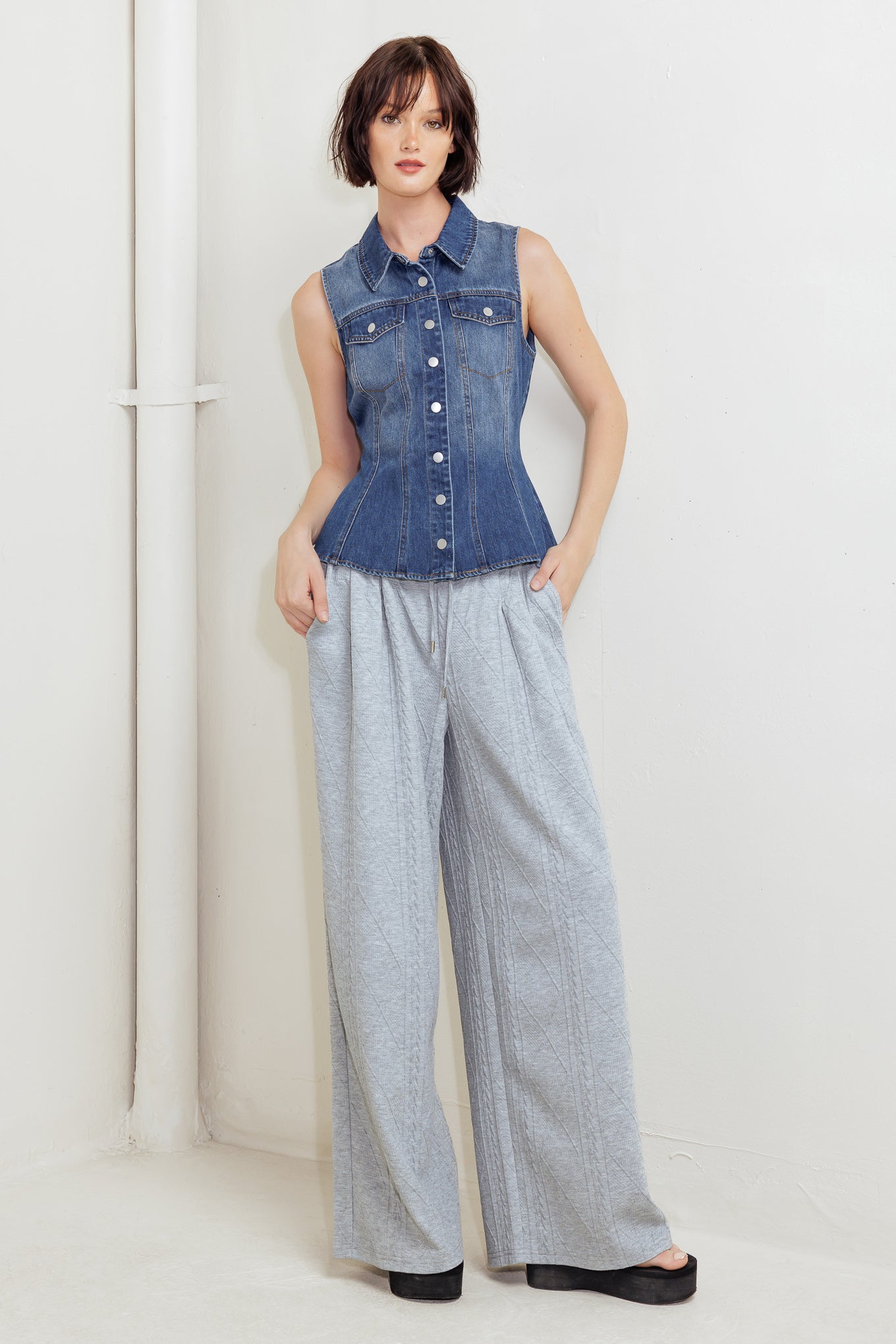 A washed denim top featuring collar, sleeveless, button down, pockets and peplum