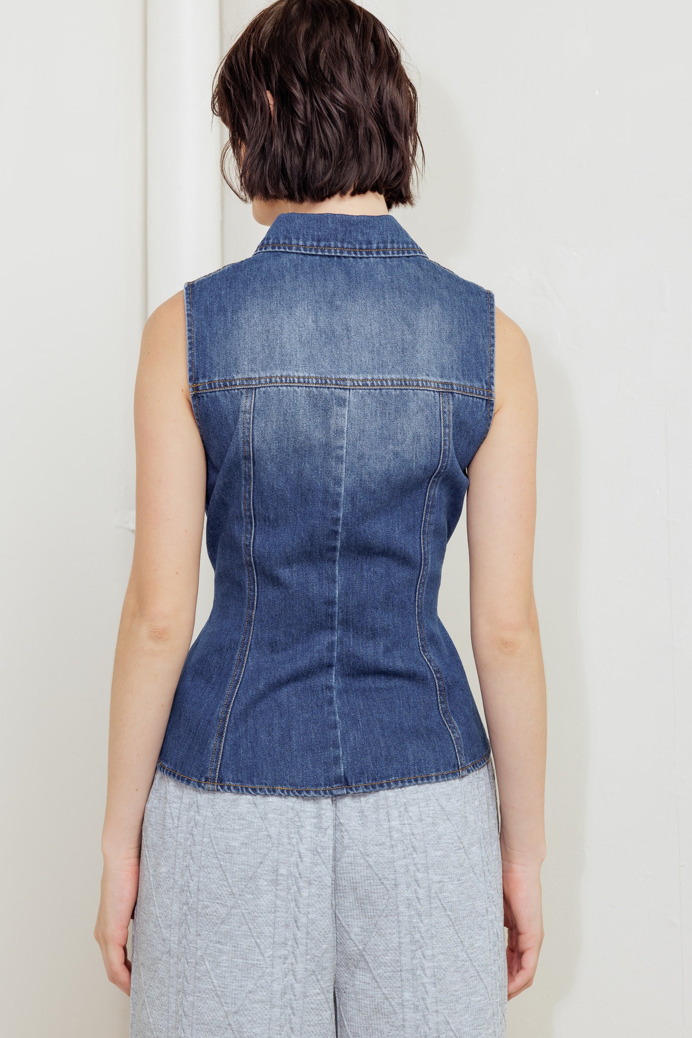 A washed denim top featuring collar, sleeveless, button down, pockets and peplum