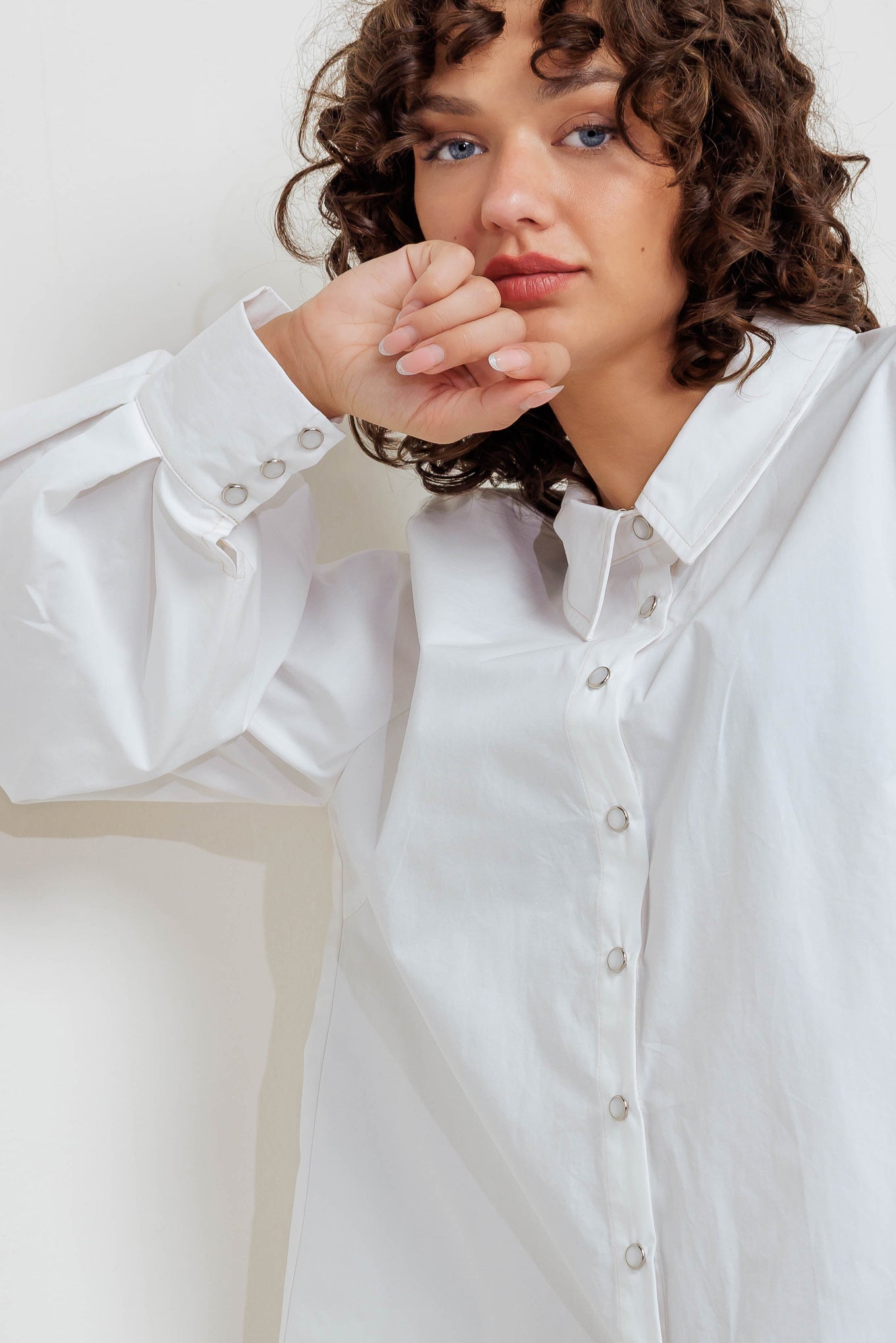 A solid white woven top featuring collar, front snap button down and long sleeve