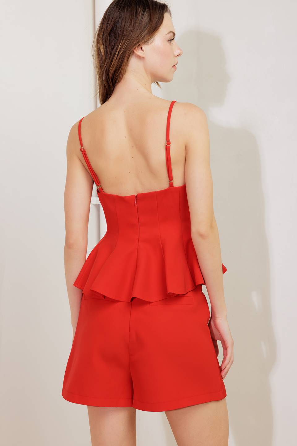 A solid woven cami top with peplum and back zipper closure.