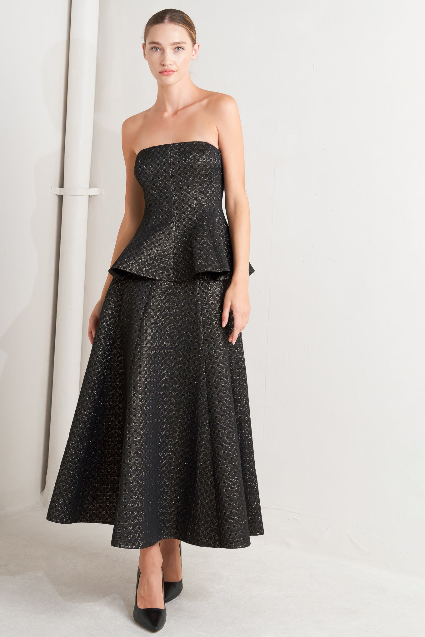 A textured metallic threaded woven top featuring strapless, peplum and back zipper closure.