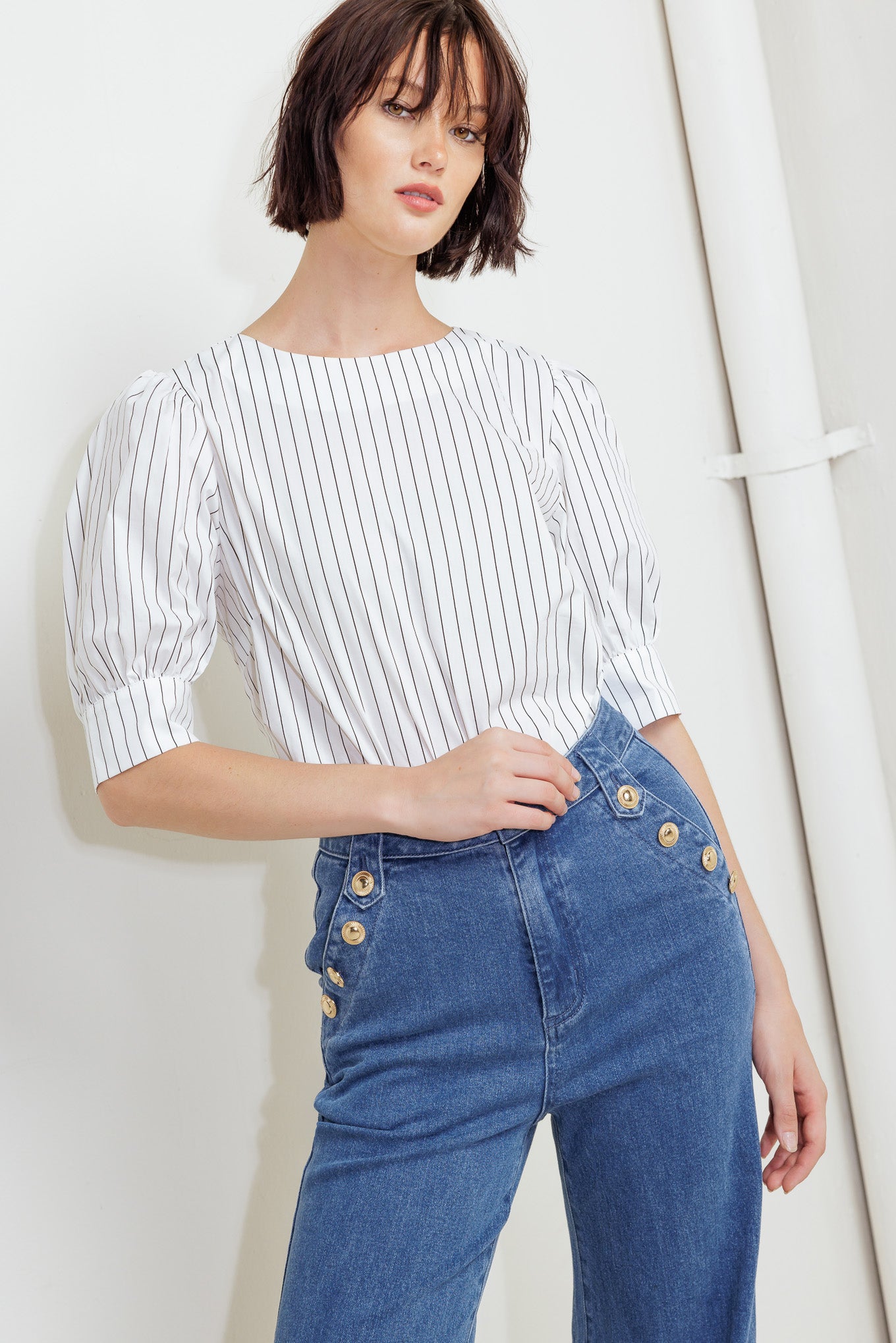 A striped woven top featuring round neckline, short puff sleeve with cuff and back button down closure
