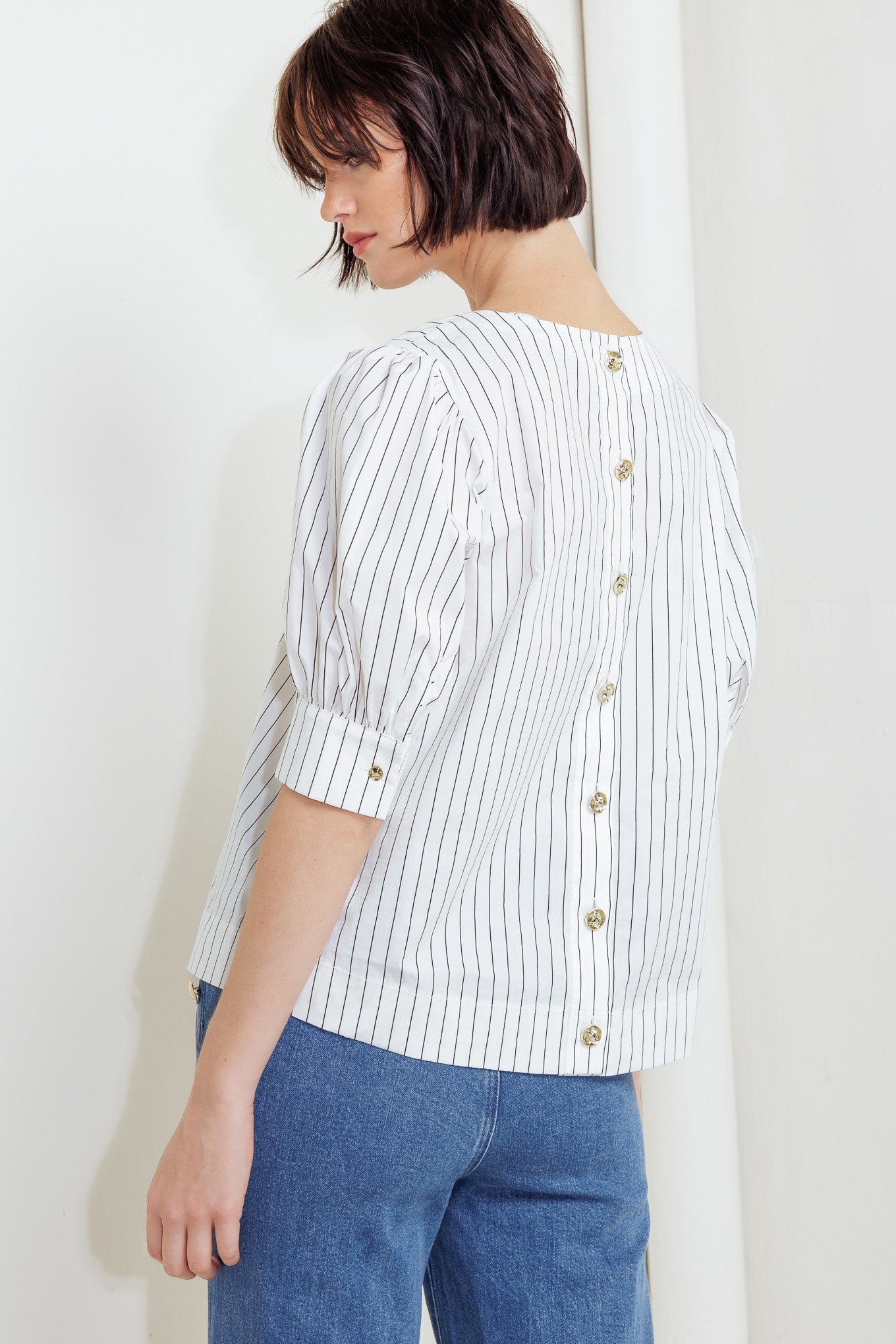 A striped woven top featuring round neckline, short puff sleeve with cuff and back button down closure
