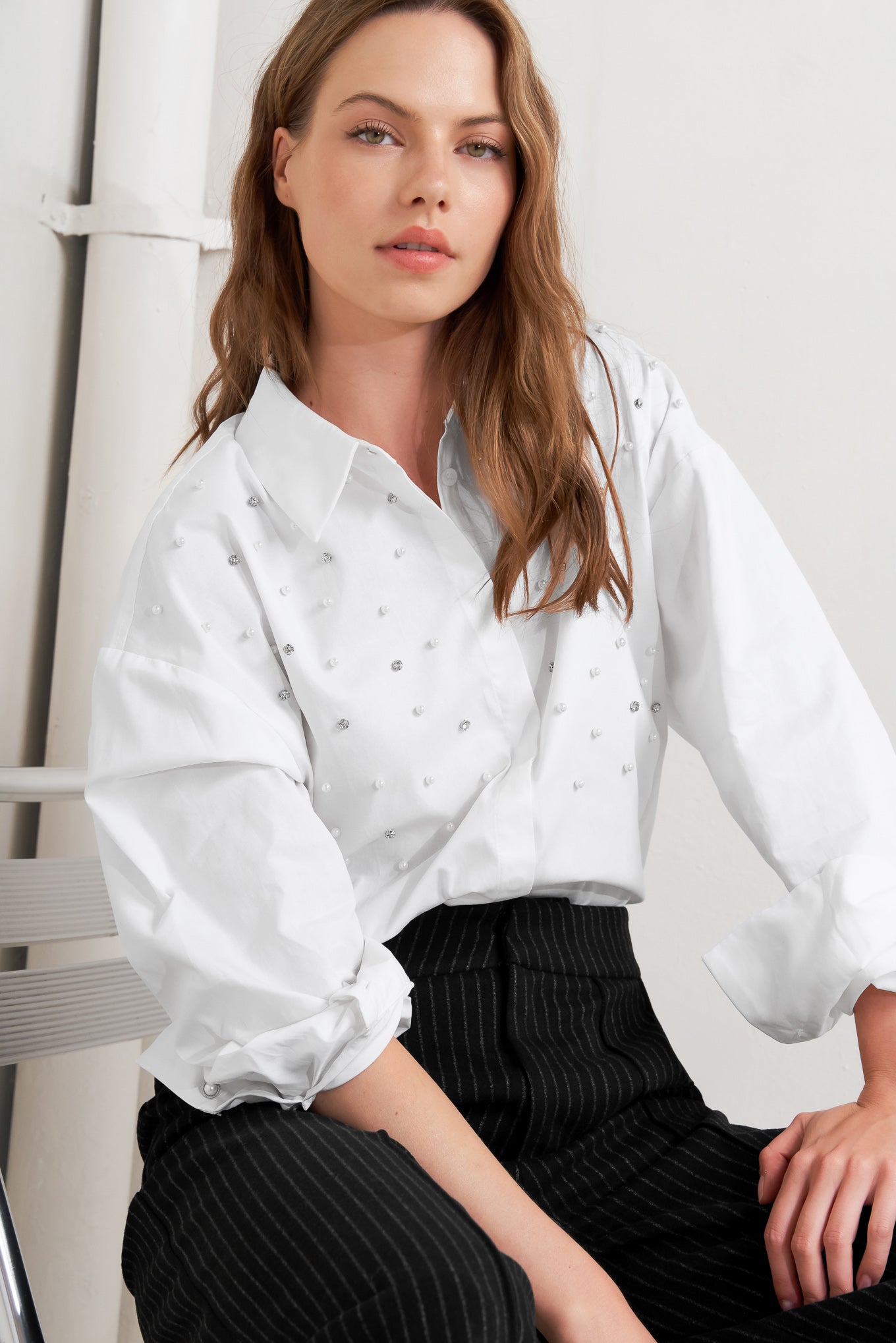 A woven shirt featuring collar, long sleeve, front button down and embellishment