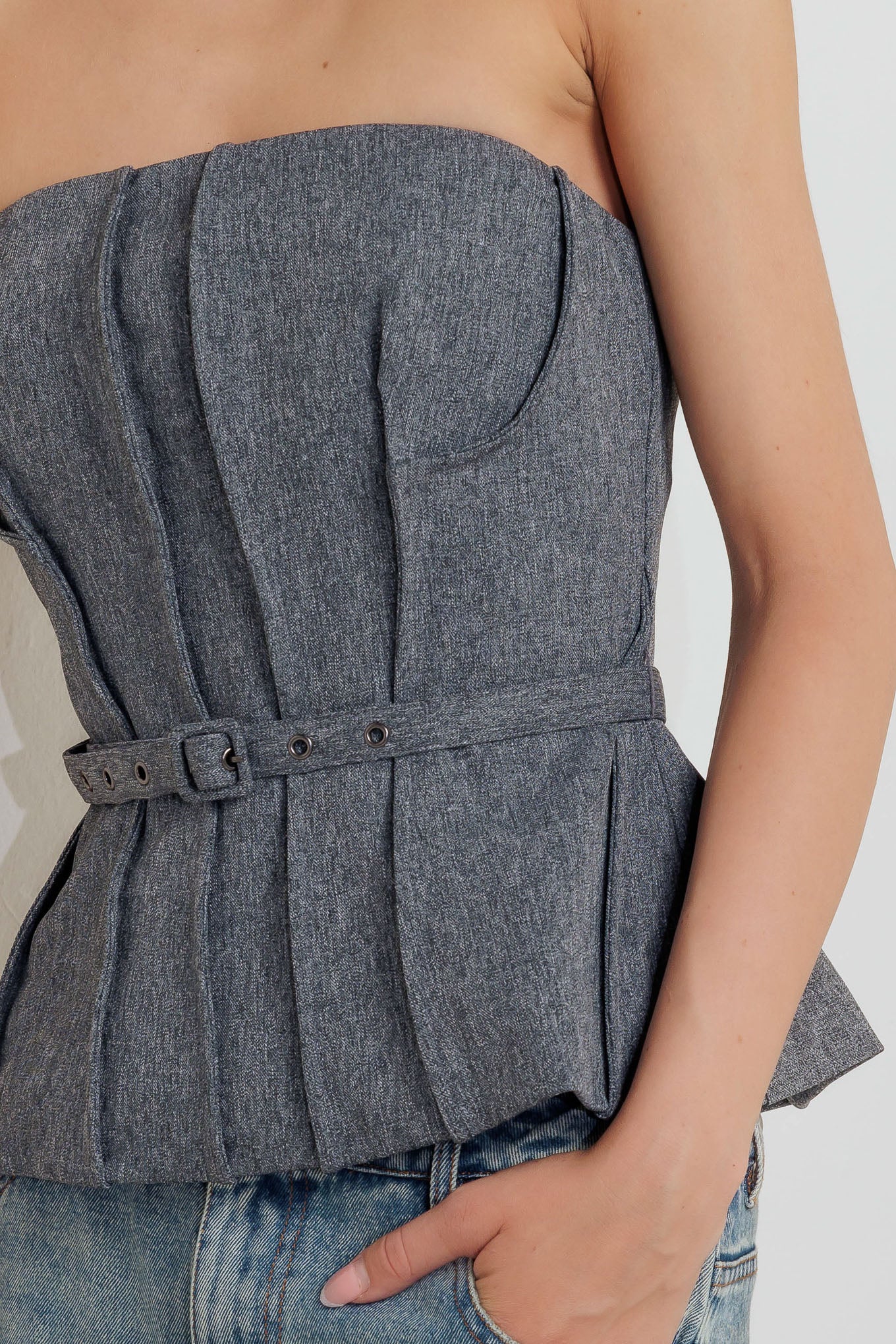 A solid woven tube top featuring self belt, peplum and back zipper closure.