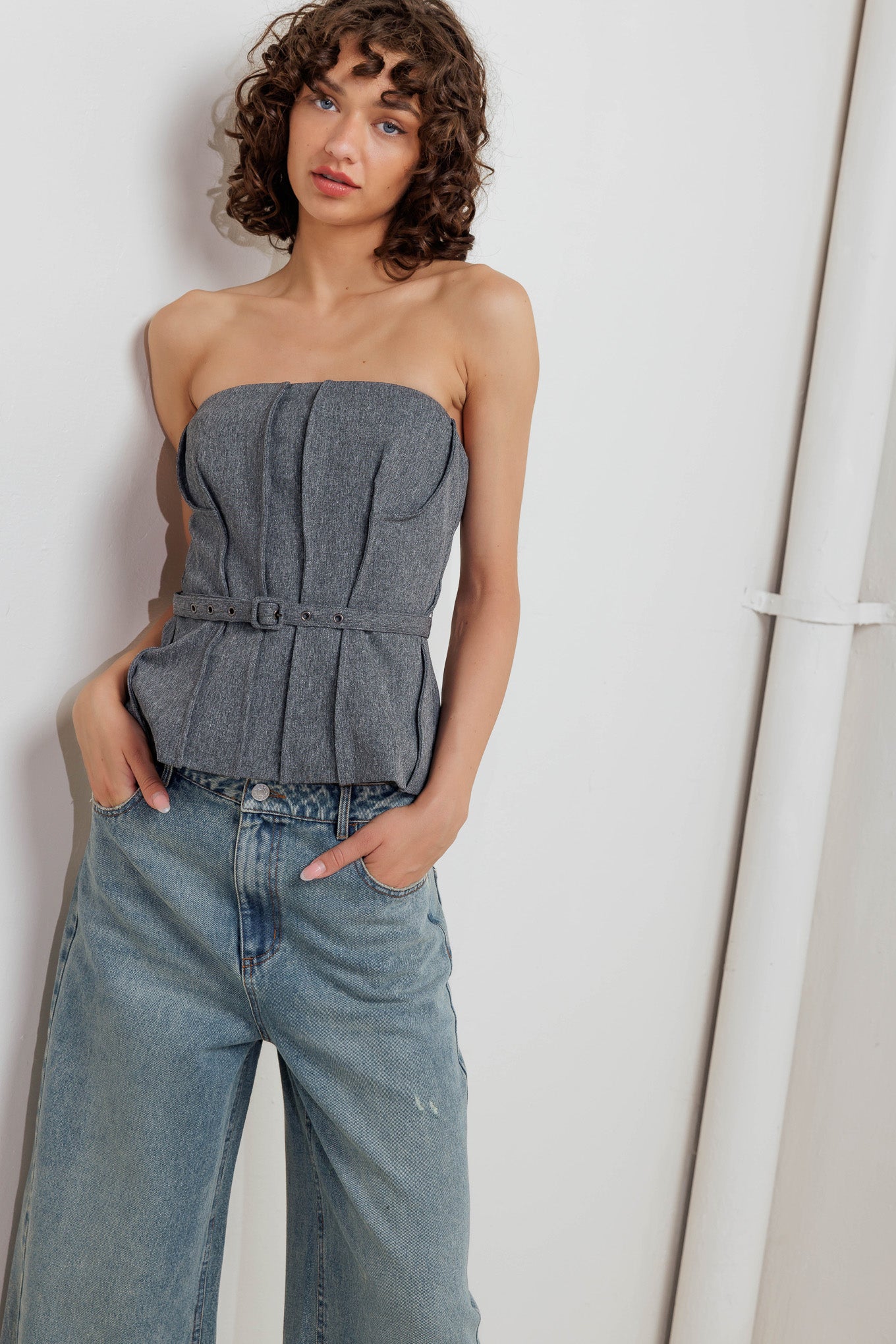 A solid woven tube top featuring self belt, peplum and back zipper closure.