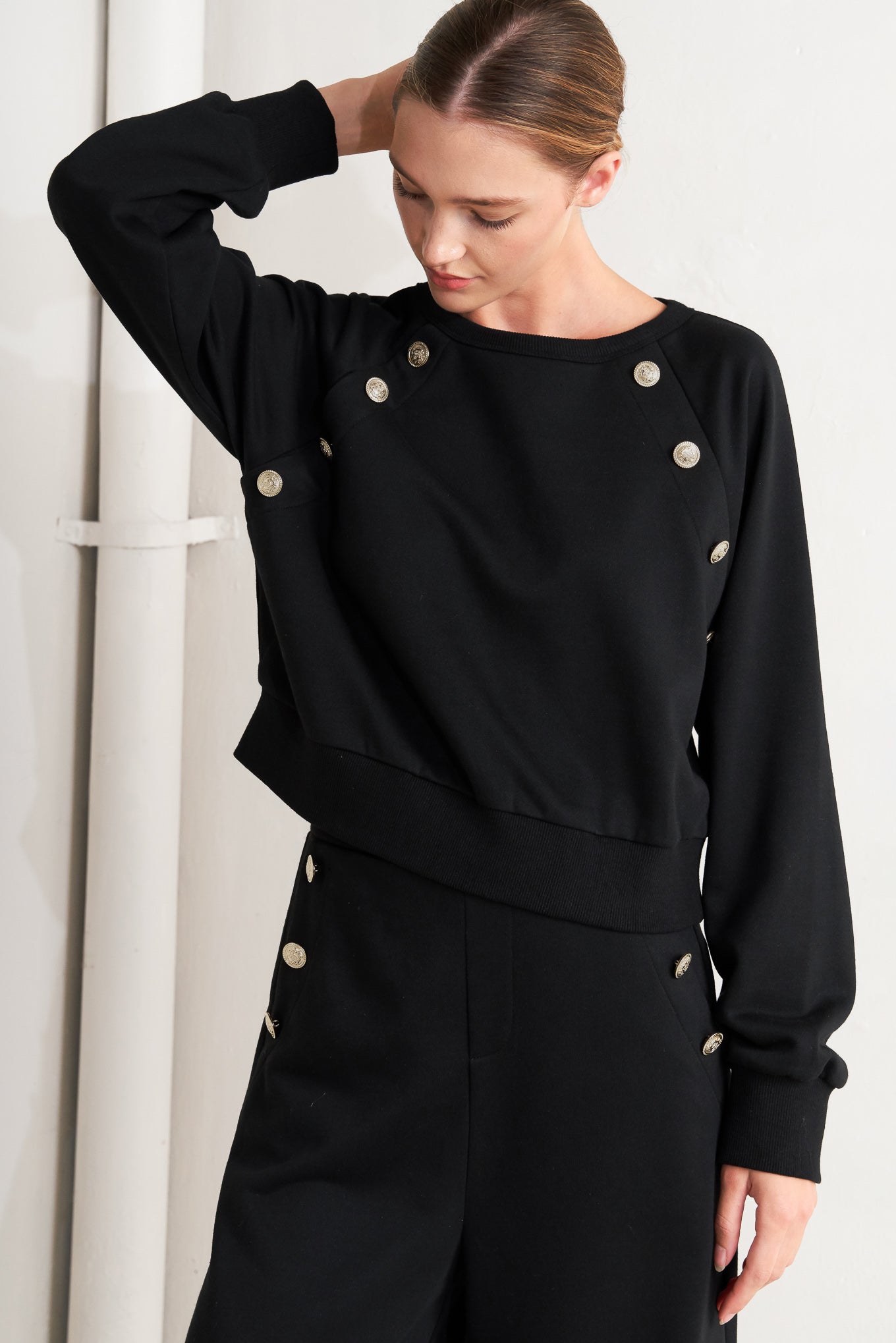 A solid woven top featuring crew neckline, long sleeve and button detail