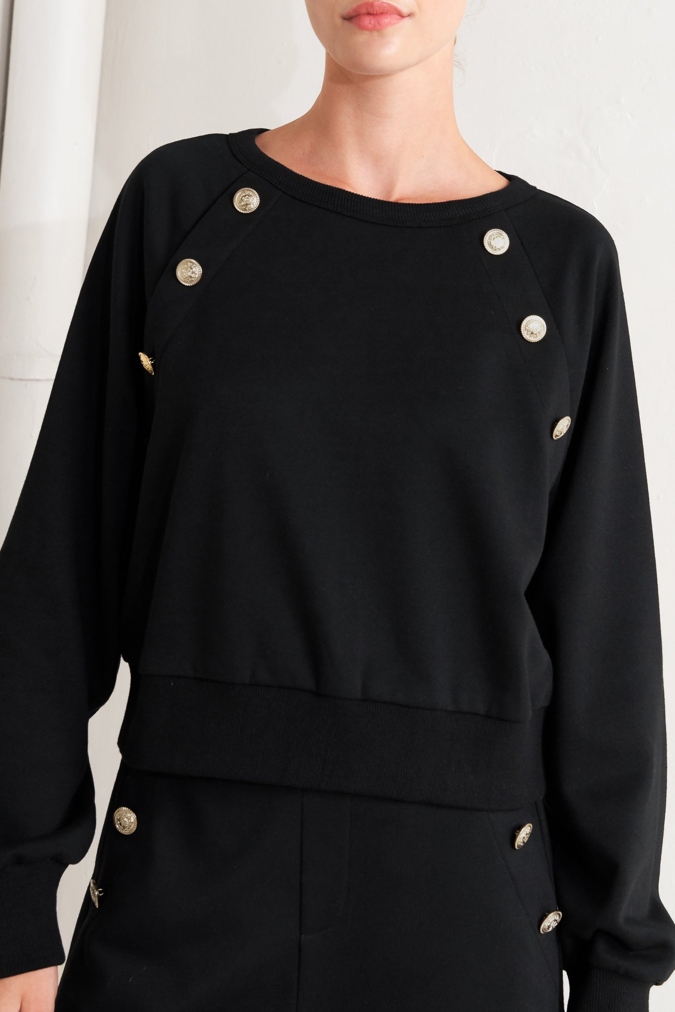 A solid woven top featuring crew neckline, long sleeve and button detail