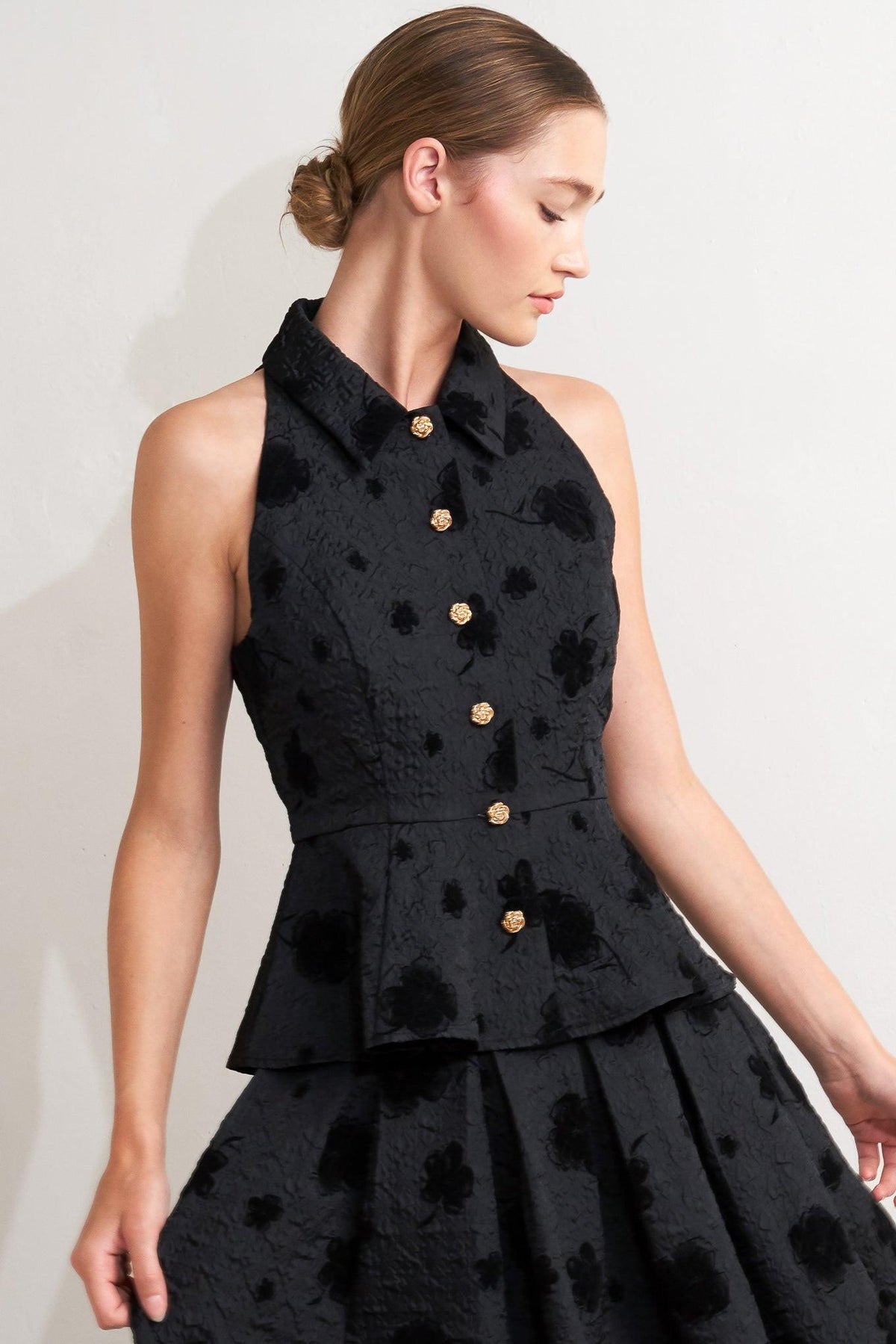 A textured woven top featuring collar, sleeveless, front button closure and peplum.