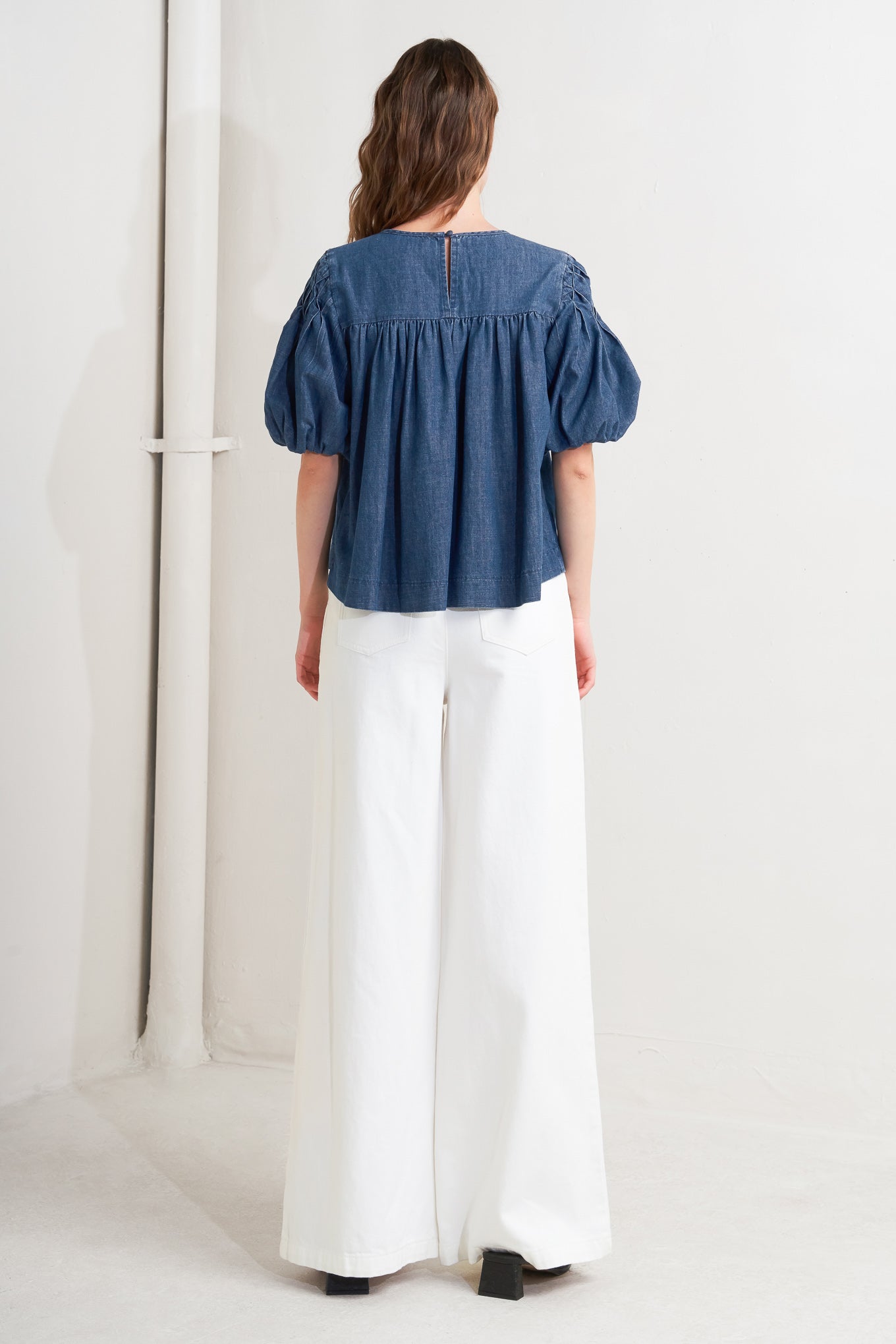 A chambray top featuring round neckline, honeycomb smocked, short bubble sleeve and back button closure