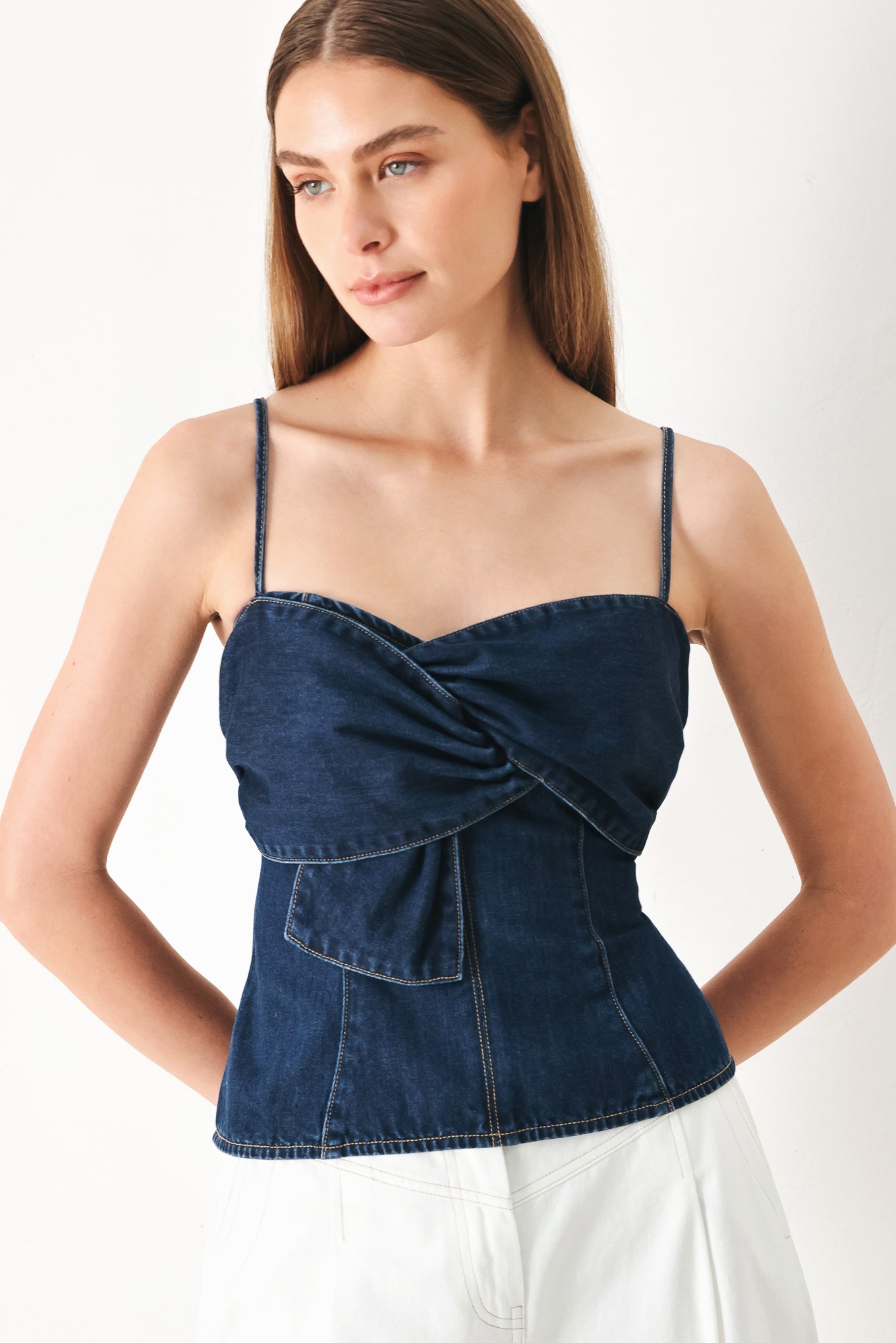 Woman wearing a denim top featuring front twist details, straps and back zipper closure | FREEMARKET | Flying Tomato