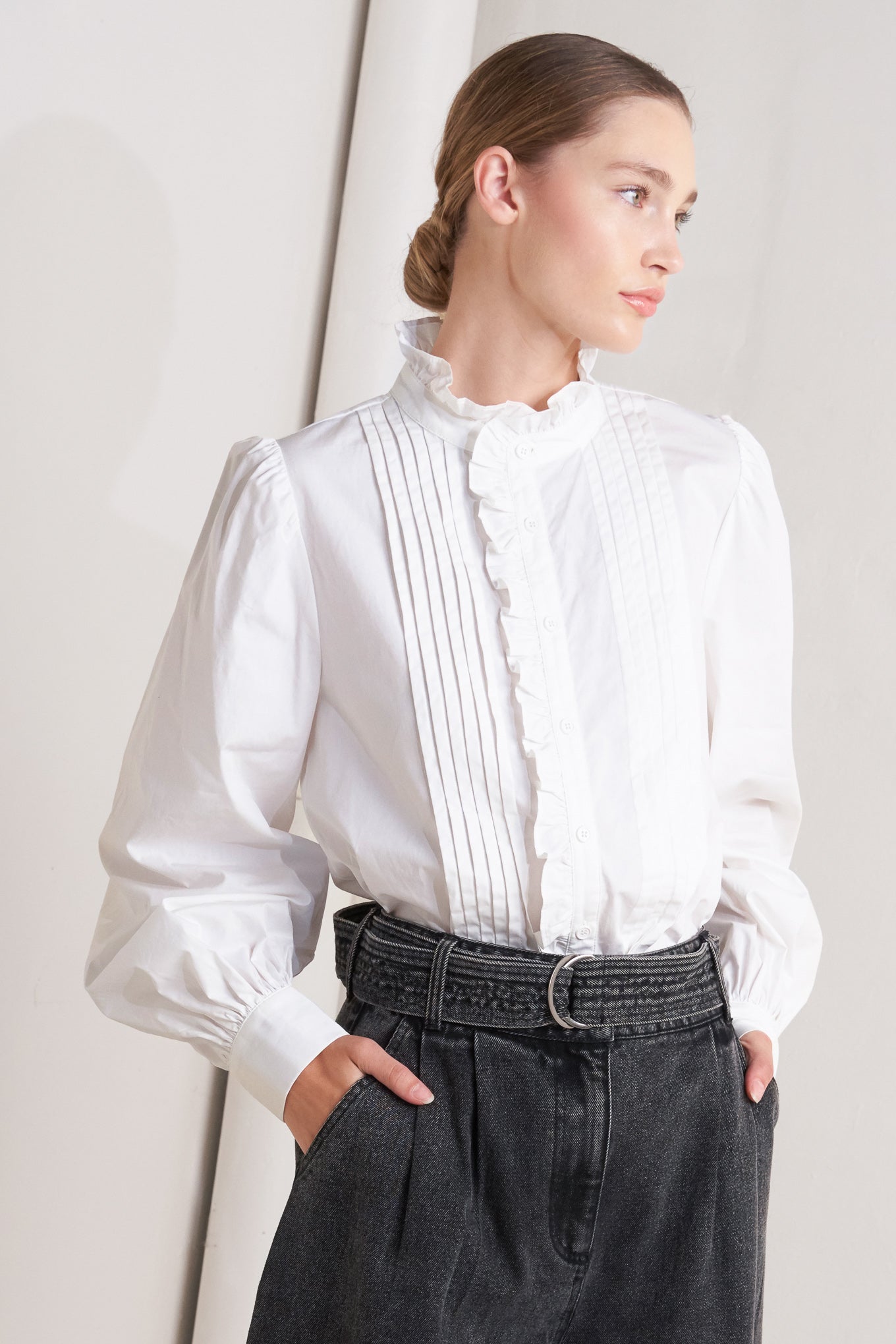 A solid woven top featuring ruffled high neckline, long sleeve and front button down closure