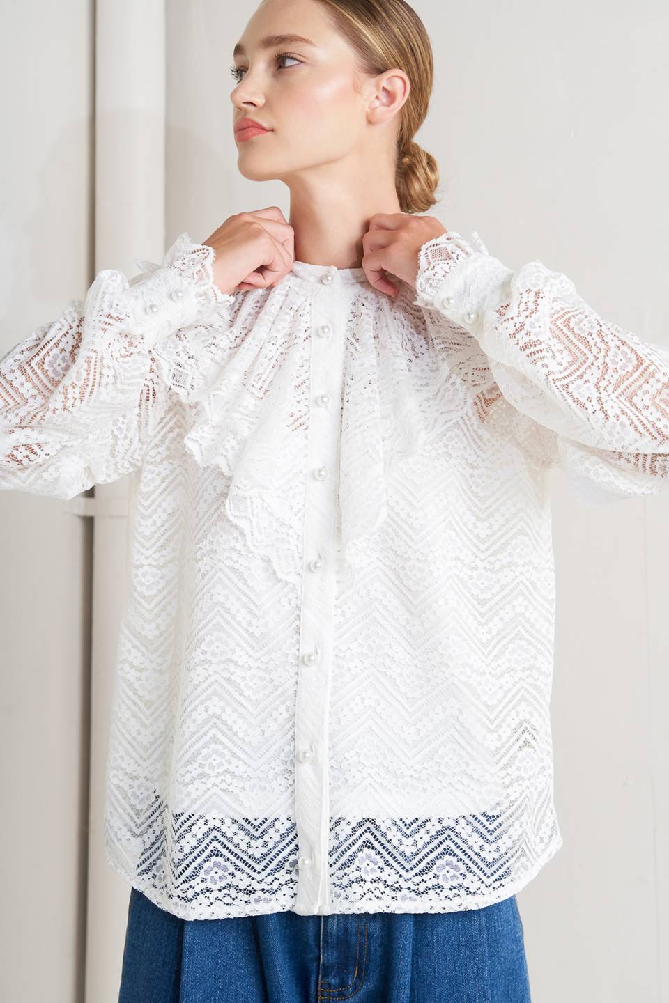 A woven lace top featuring high neckline, ruffles, long sleeve with cuff, button down closure and cami