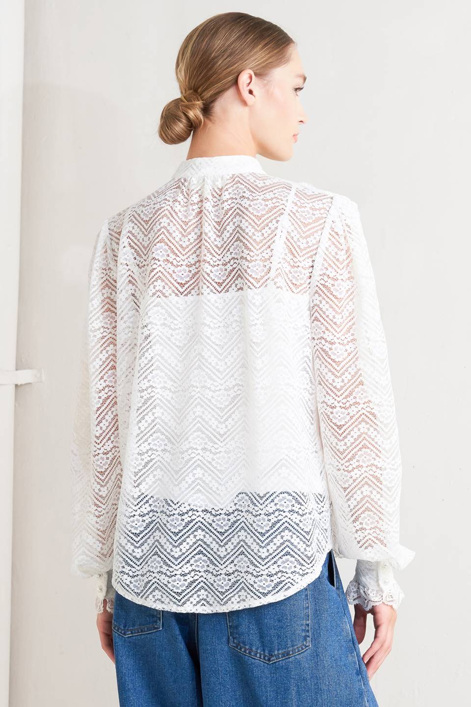 A woven lace top featuring high neckline, ruffles, long sleeve with cuff, button down closure and cami