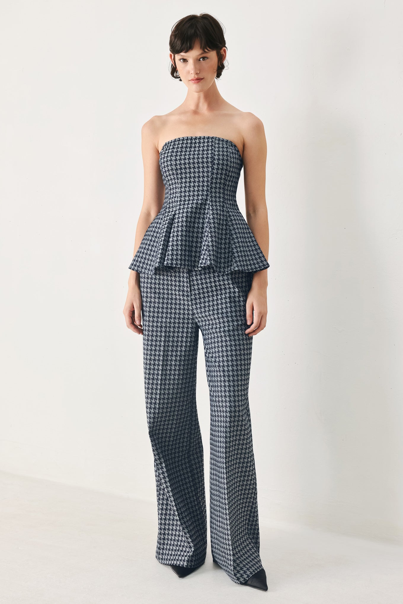 Woman wearing a strapless houndstooth patterned tube top with peplum and back zipper closure | FREEMARKET