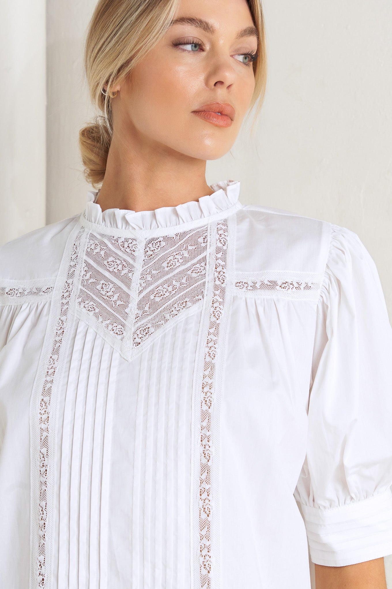 A solid woven top featuring ruffled high neck, pintuck and lace inset, short puff sleeve and back neck button closure
Details:
Self: 100% Cotton Exclusive of Decoration
Size & Fit
- Model is 5`8" And Wearing Size Small
- Measurements Taken From Size Small
- Approx. Length: 23"