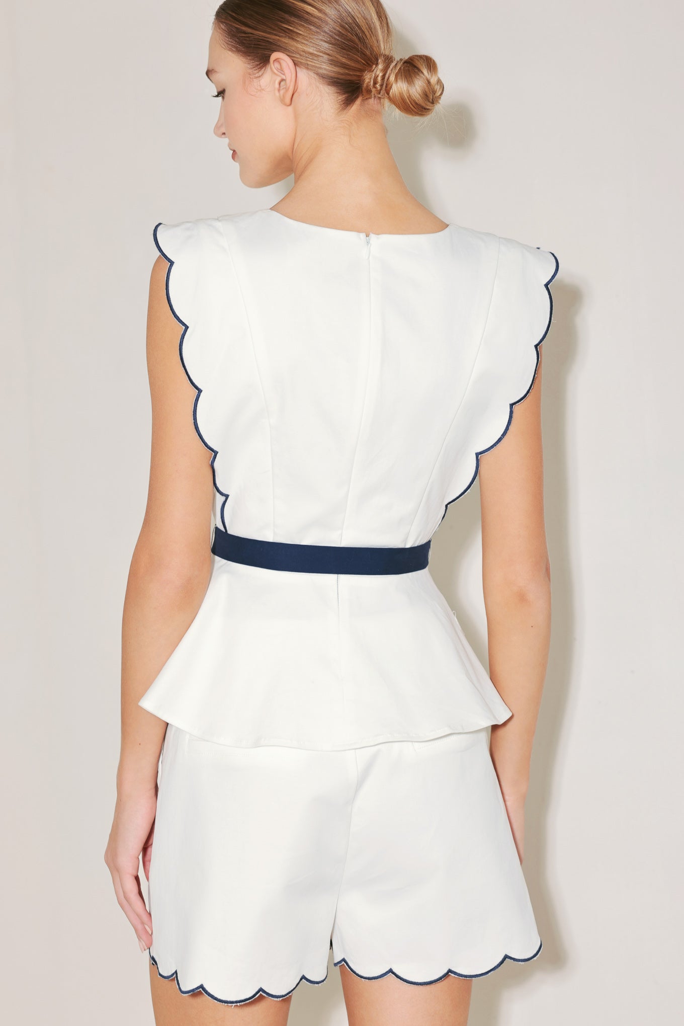 A solid woven top featuring round neckline, button down detail, scallop edge, contrasting tie and back zipper closure. Matching short FP1901-T
Details:
Self : 97% Cotton 3% Spandex
Contrast : 97% Cotton 3% Spandex
Size & Fit
- Model is 5`8" And Wearing Size Small
- Measurements Taken From Size Small
- Approx. Length: 23"