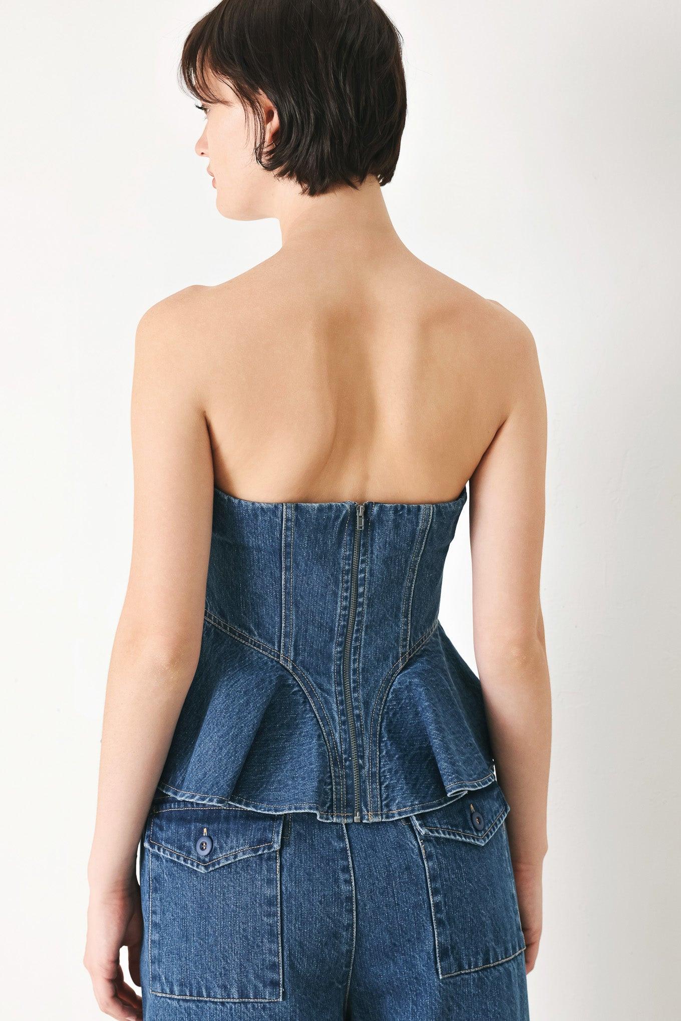 A washed denim top featuring strapless, ruffled peplum and back zipper closure