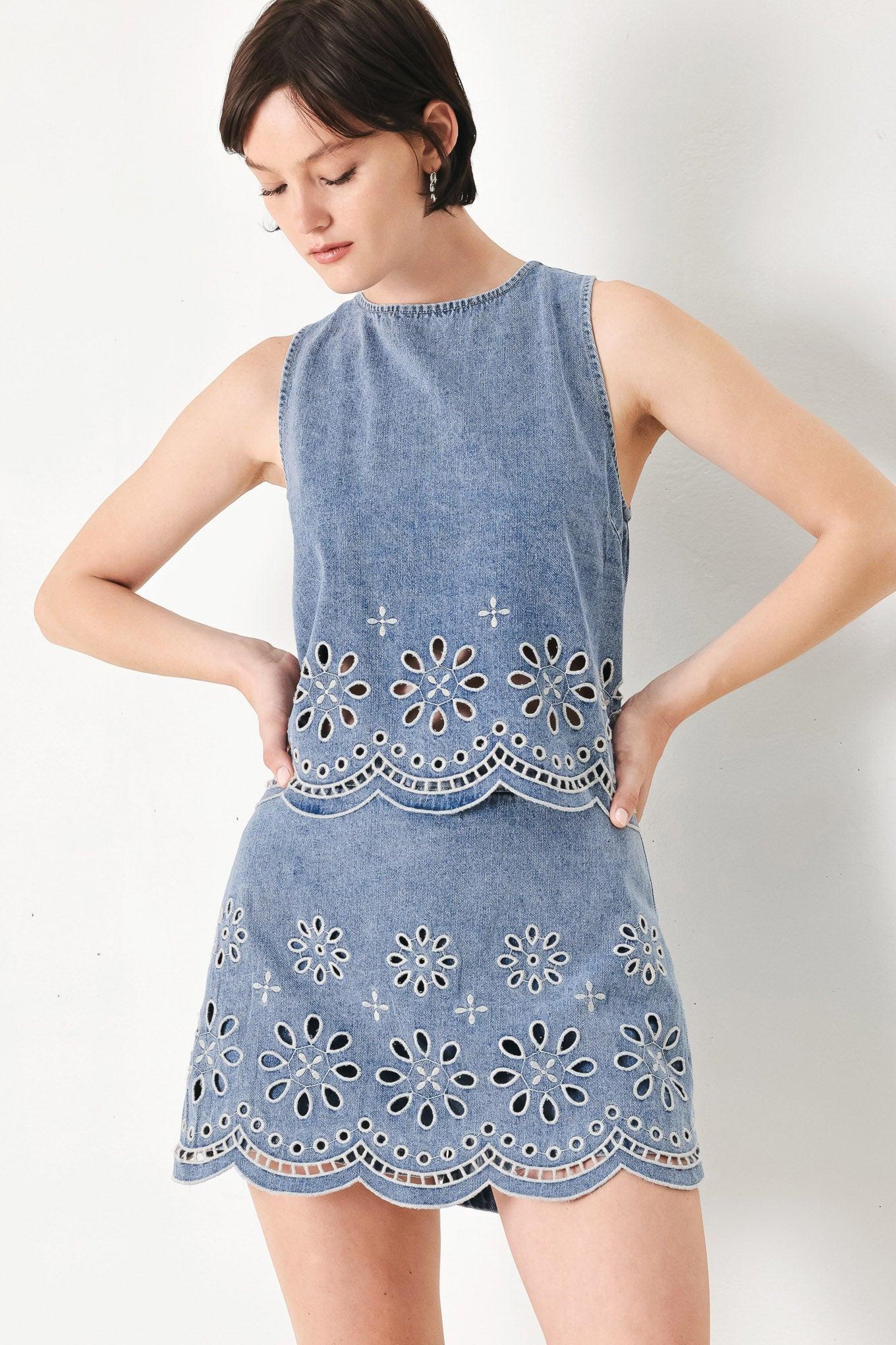 A washed denim top featuring round neckline, sleeveless, eyelet cut out and scallop hem with back tie closure