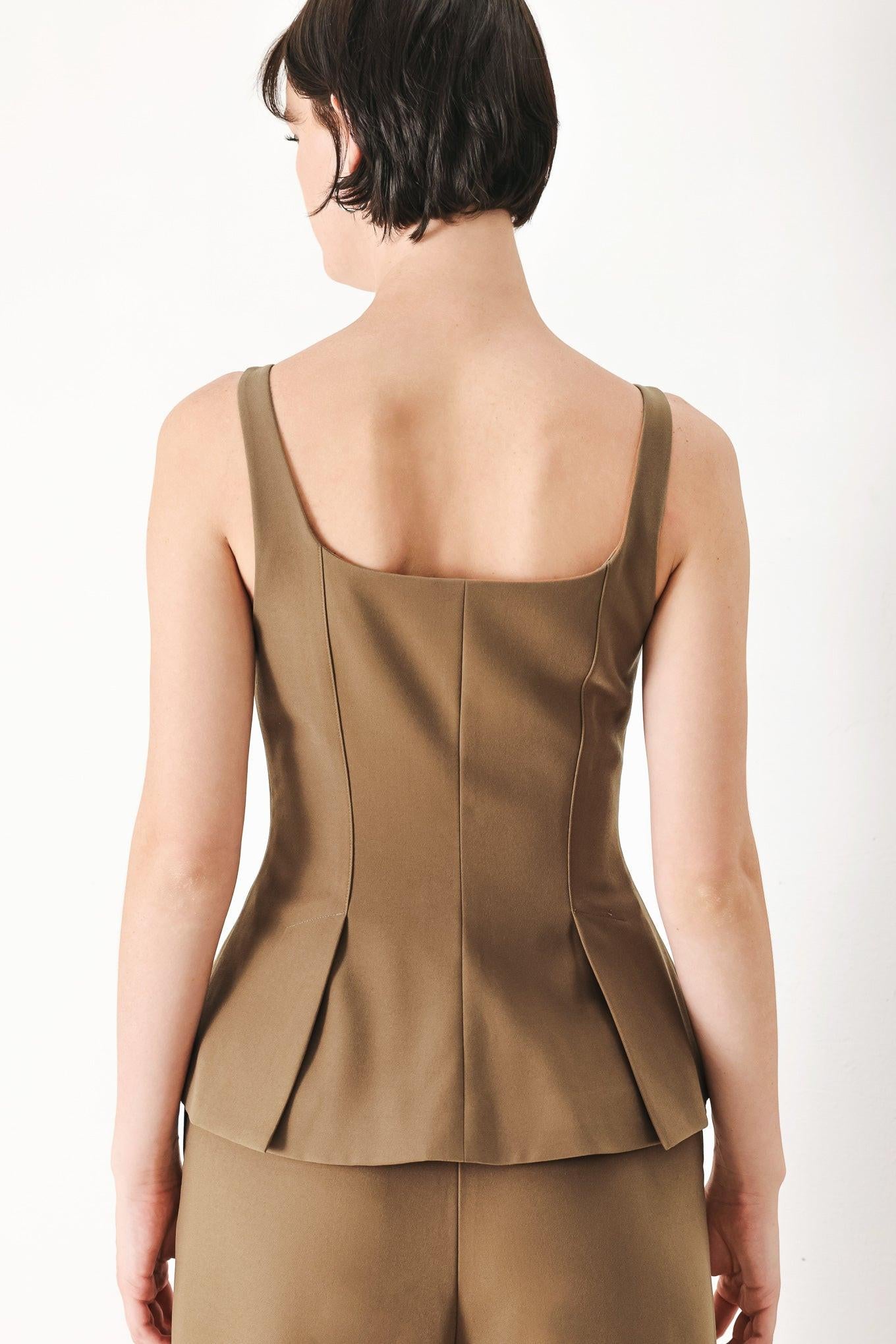 A solid woven top with square neckline, sleeveless, front zipper closure and peplum.