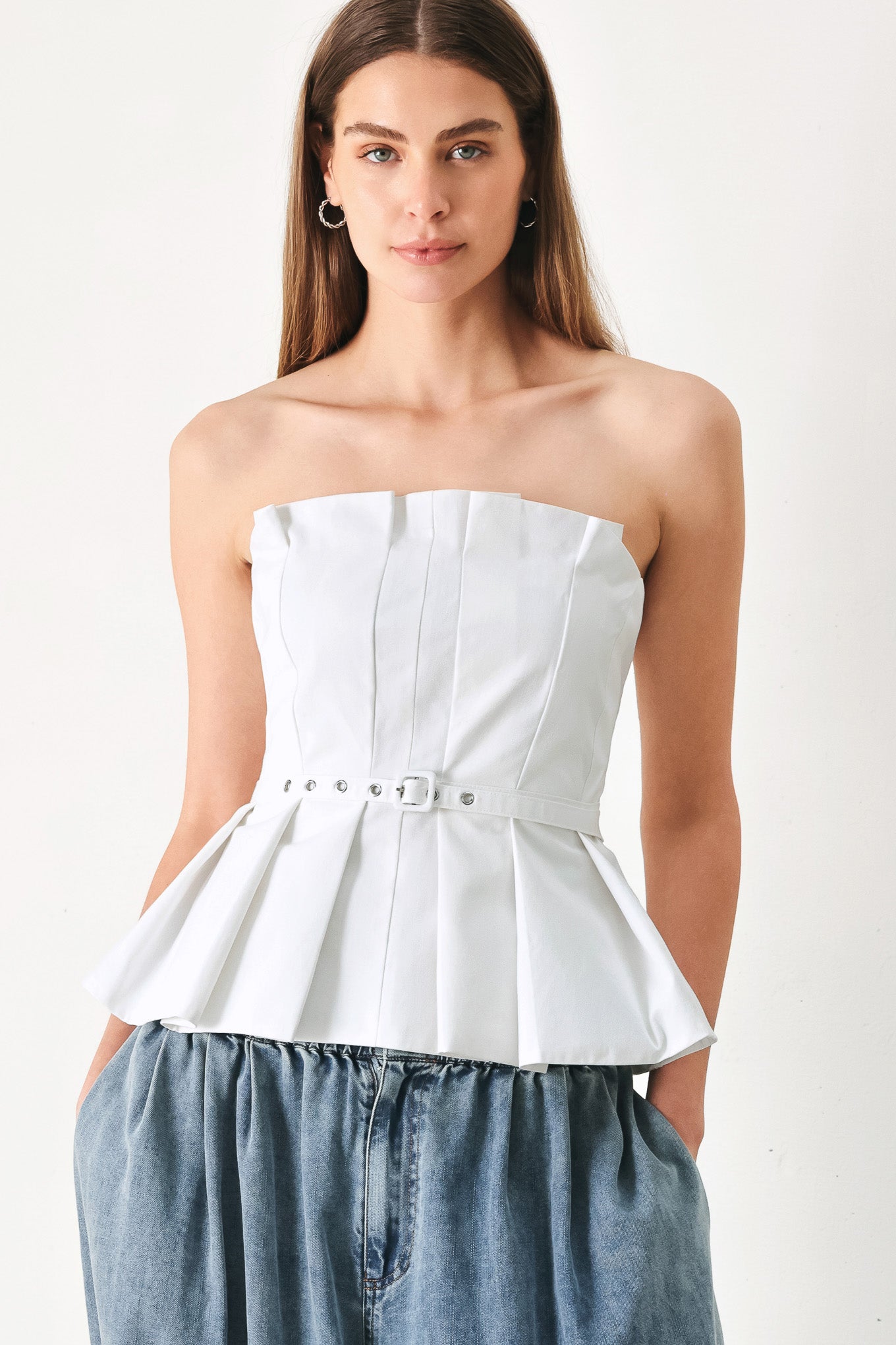 Woman wearing a white strapless top with a belt featuring knife pleats | Flying Tomato