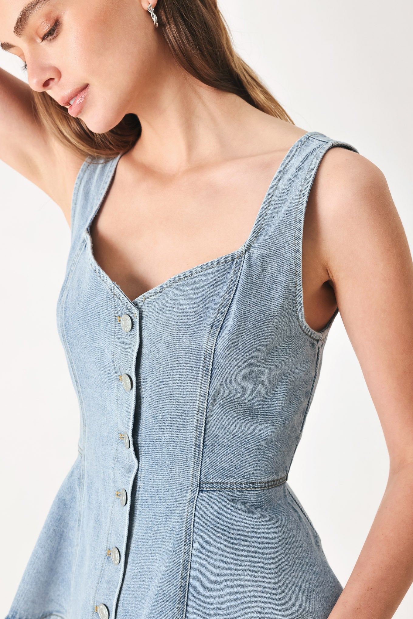Woman wearing a sleeveless denim peplum top featuring Queen Anne neckline, sleeveless, front button down | FREEMARKET | Flying Tomato
