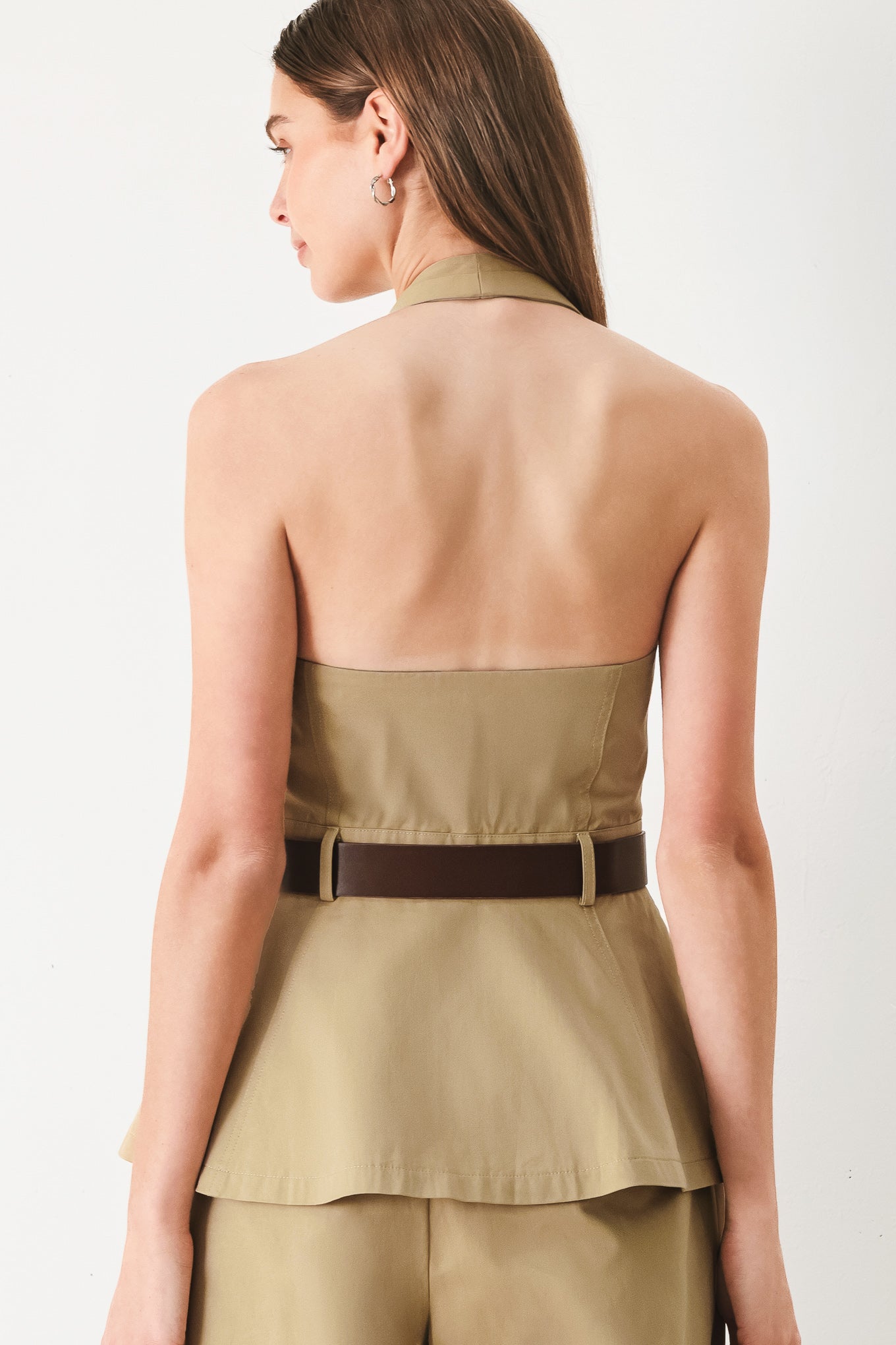 Woman wearing a beige halter peplum top with a brown belt with front closure | FREEMARKET | Flying Tomato
