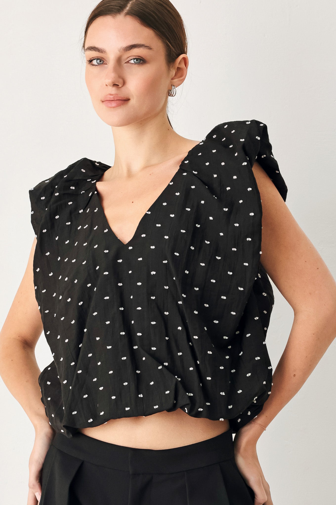 Woman wearing a black polka dot top featuring V neckline with bubble sleeve and waist | FREEMARKET