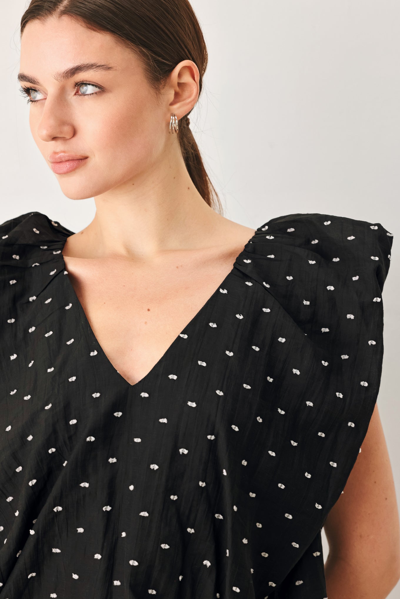 Woman wearing a black polka dot top featuring V neckline with bubble sleeve and waist | FREEMARKET