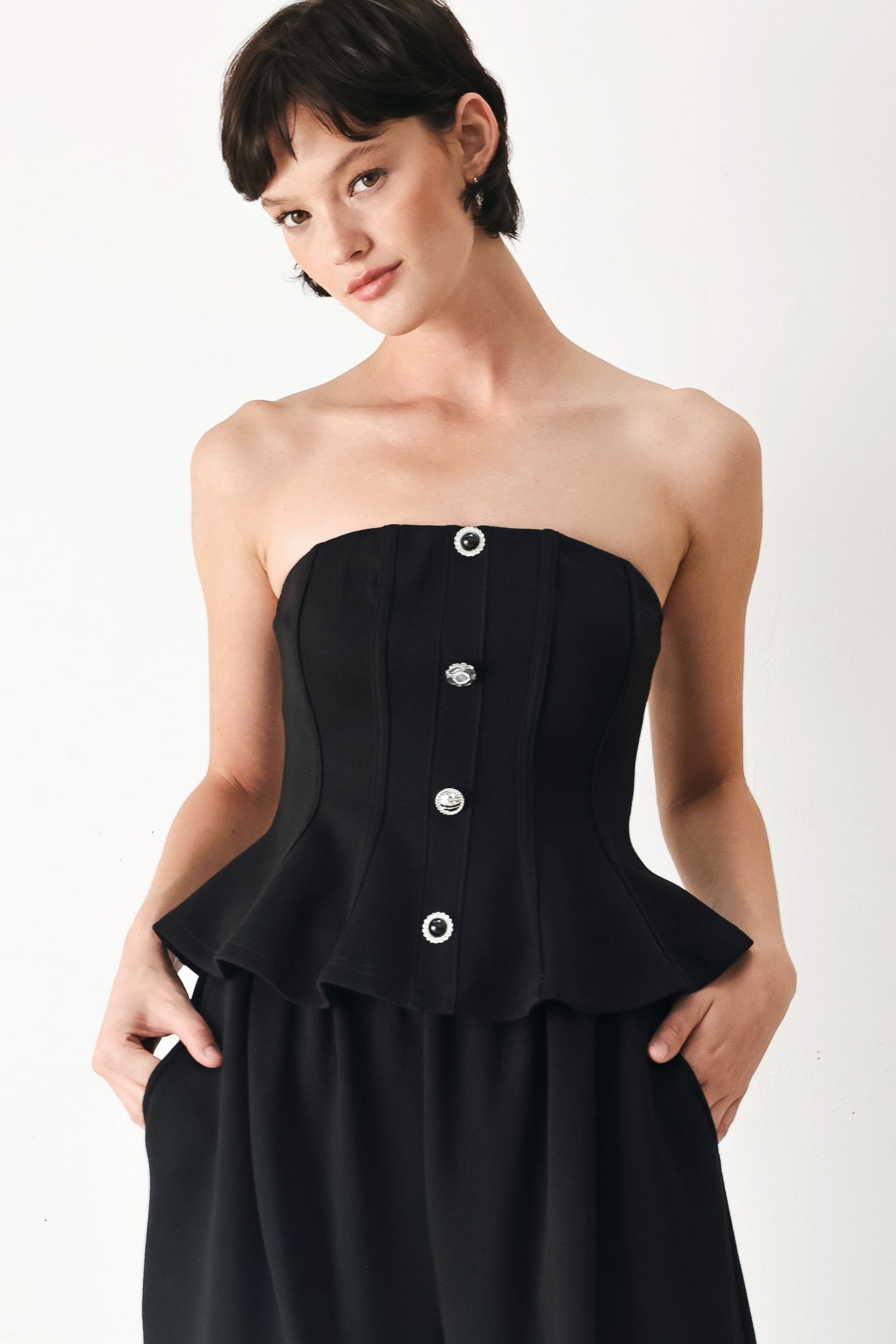 Woman wearing a black strapless tube top with buttons down the front | FREEMARKET