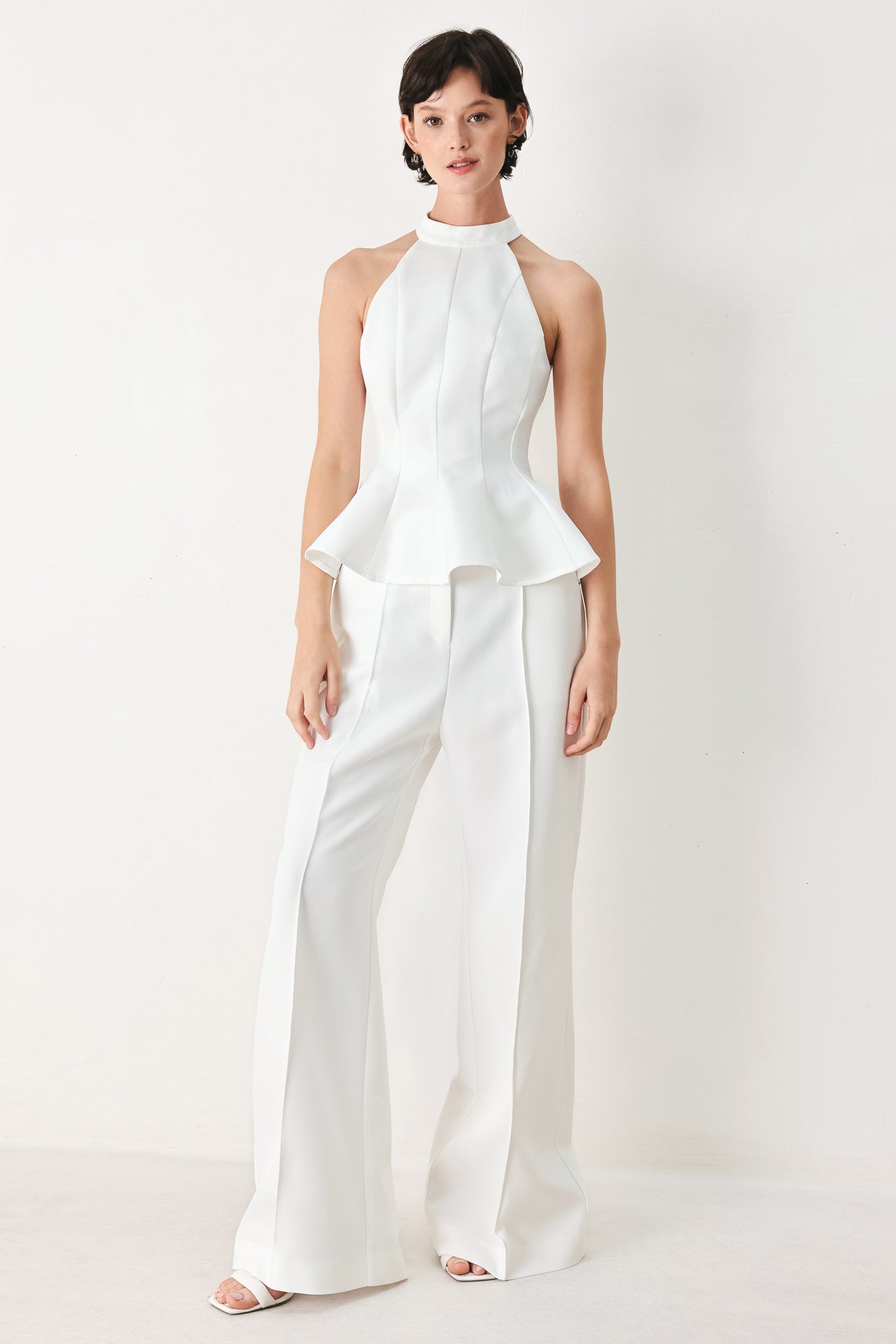 Woman wearing a white peplum top featuring halter neckline and back zipper closure | FREEMARKET