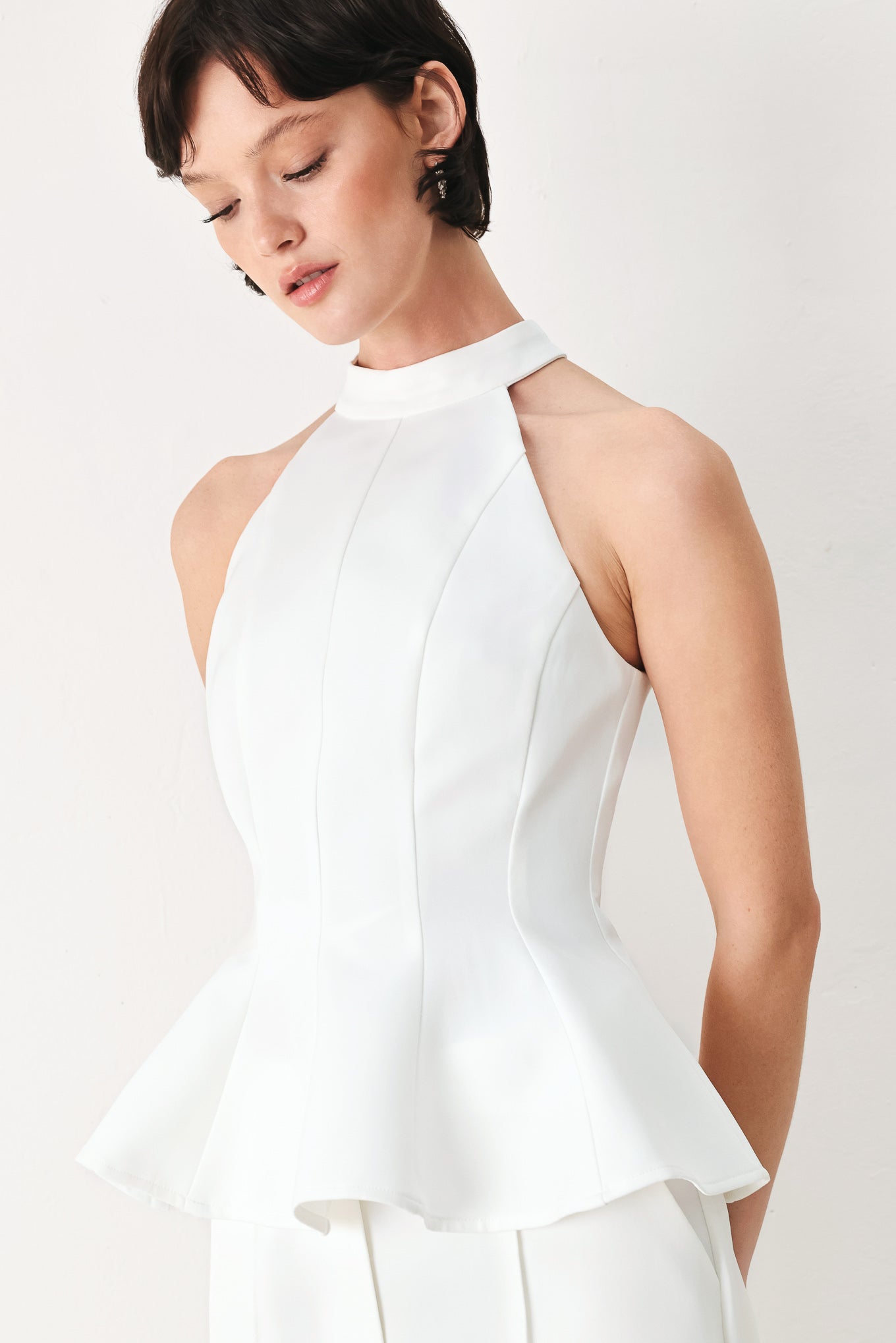 Woman wearing a white peplum top featuring halter neckline and back zipper closure | FREEMARKET