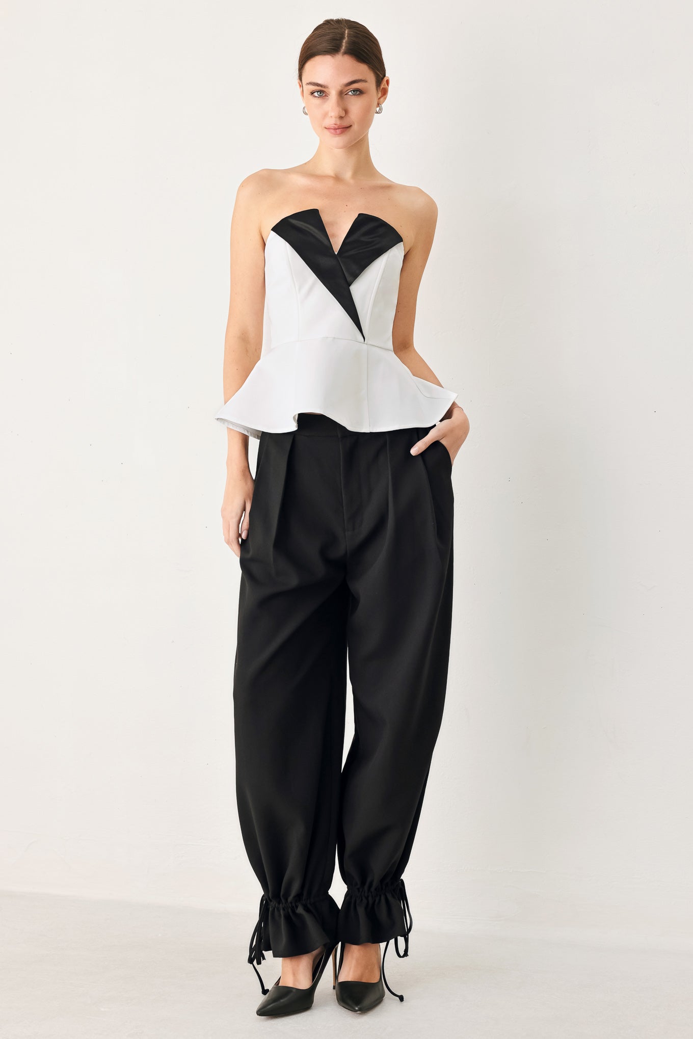 Woman wearing a black and white strapless top with a peplum effect | FREEMARKET