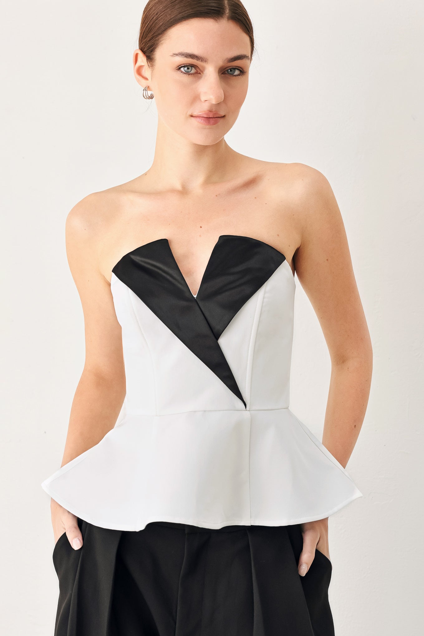 Woman wearing a black and white strapless top with a peplum effect | FREEMARKET