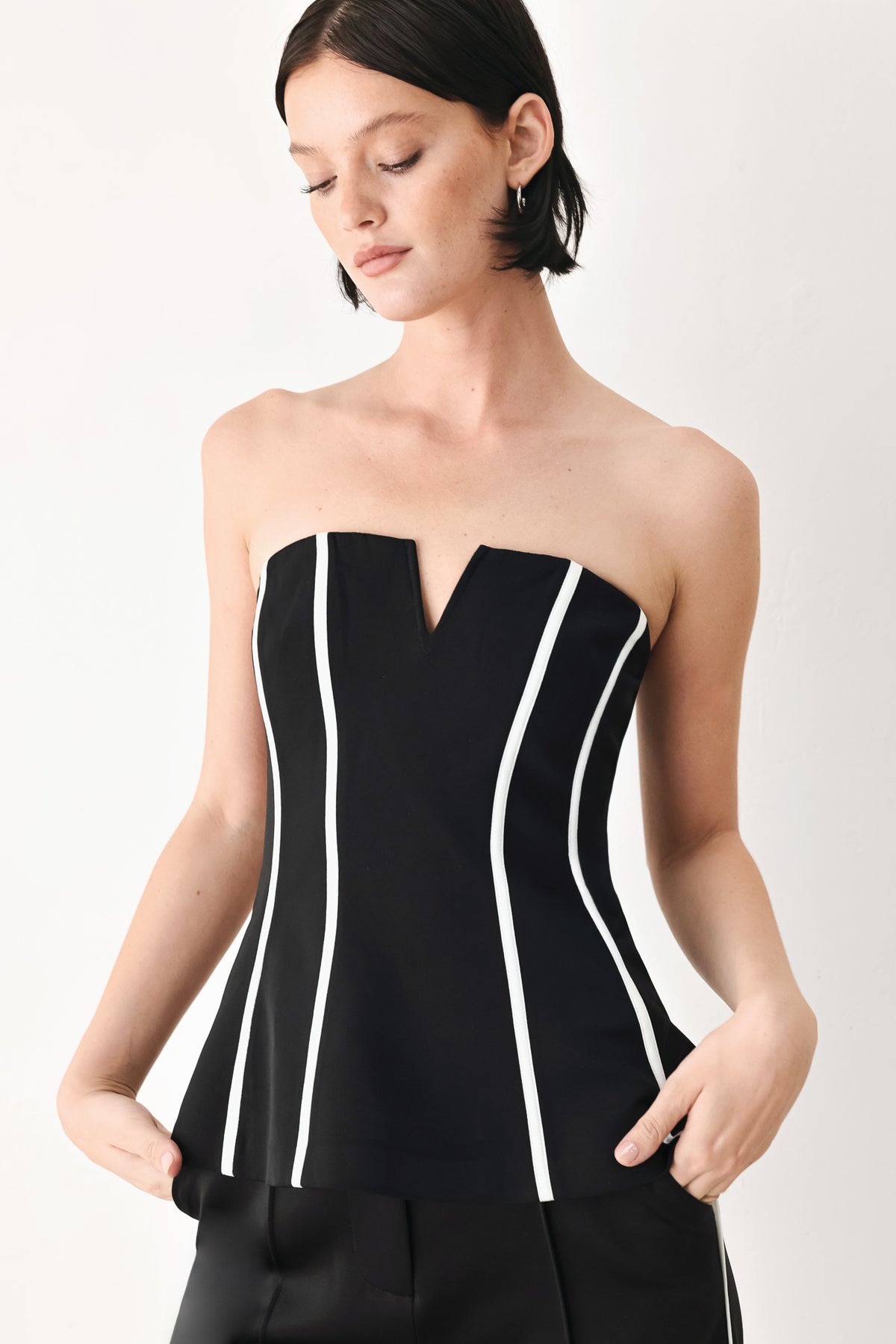 A woman wearing a strapless black corset-style top with bold white vertical stripes | FREEMARKET