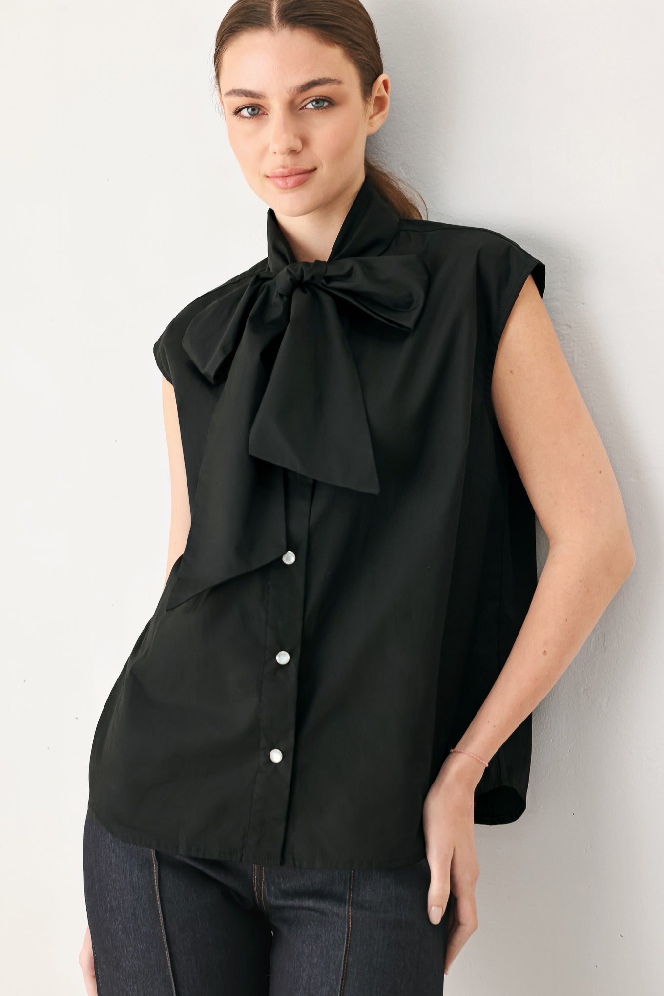 Woman wearing a black woven top with front bow tie and button down | FREEMARKET