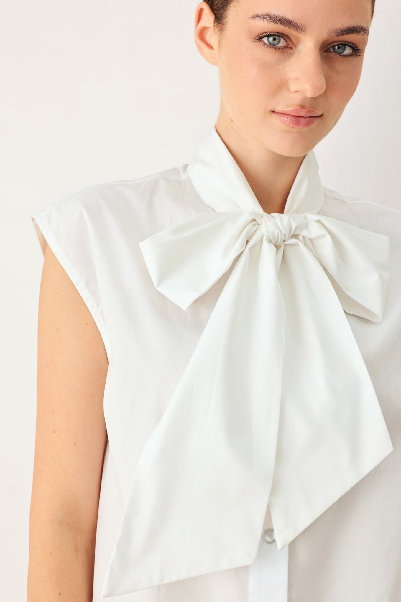 Woman wearing a white woven top with front bow tie and button down | FREEMARKET