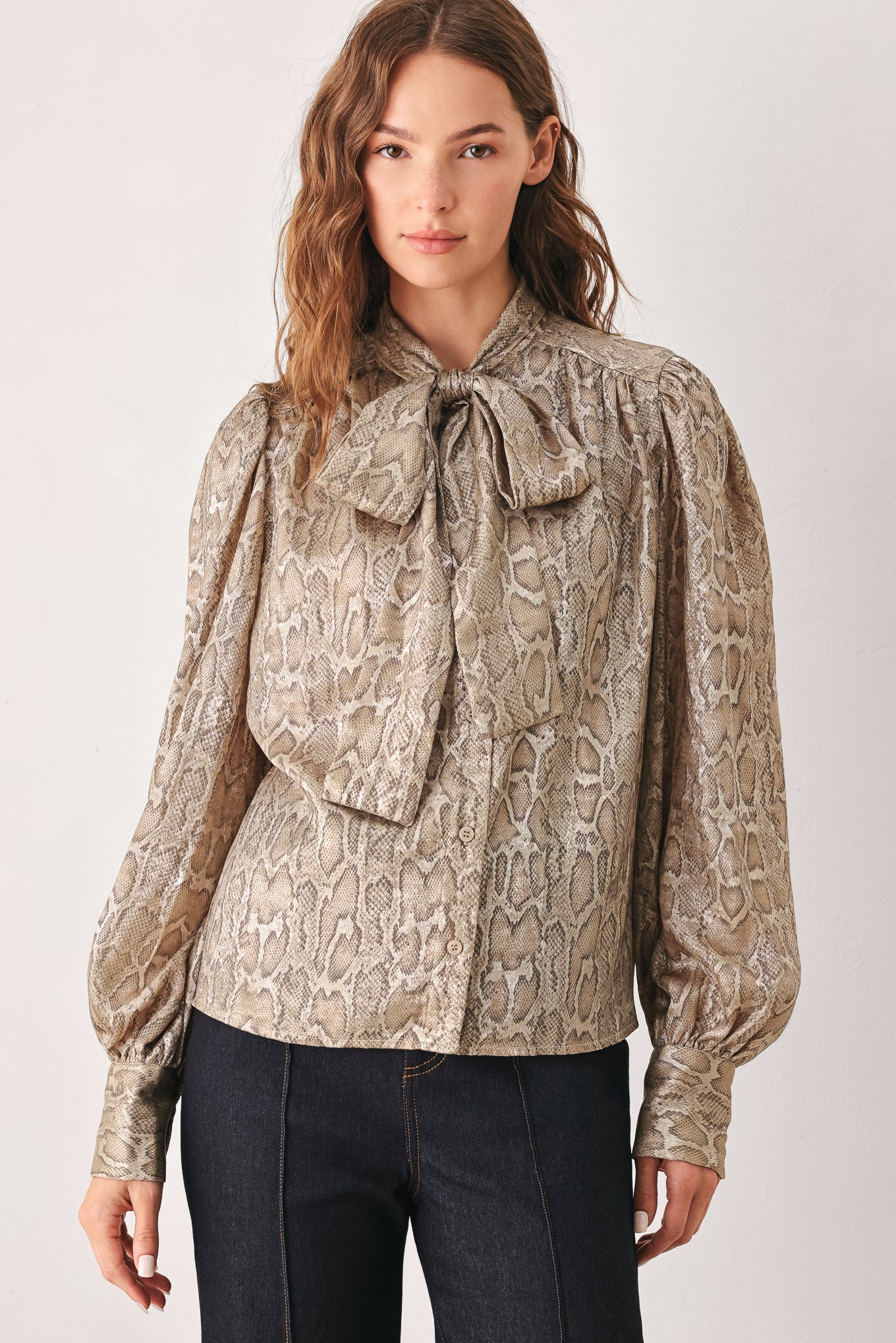 A woman modeling a long-sleeve brown and gold snake-patterned blouse with a tie-neck detail | FREEMARKET