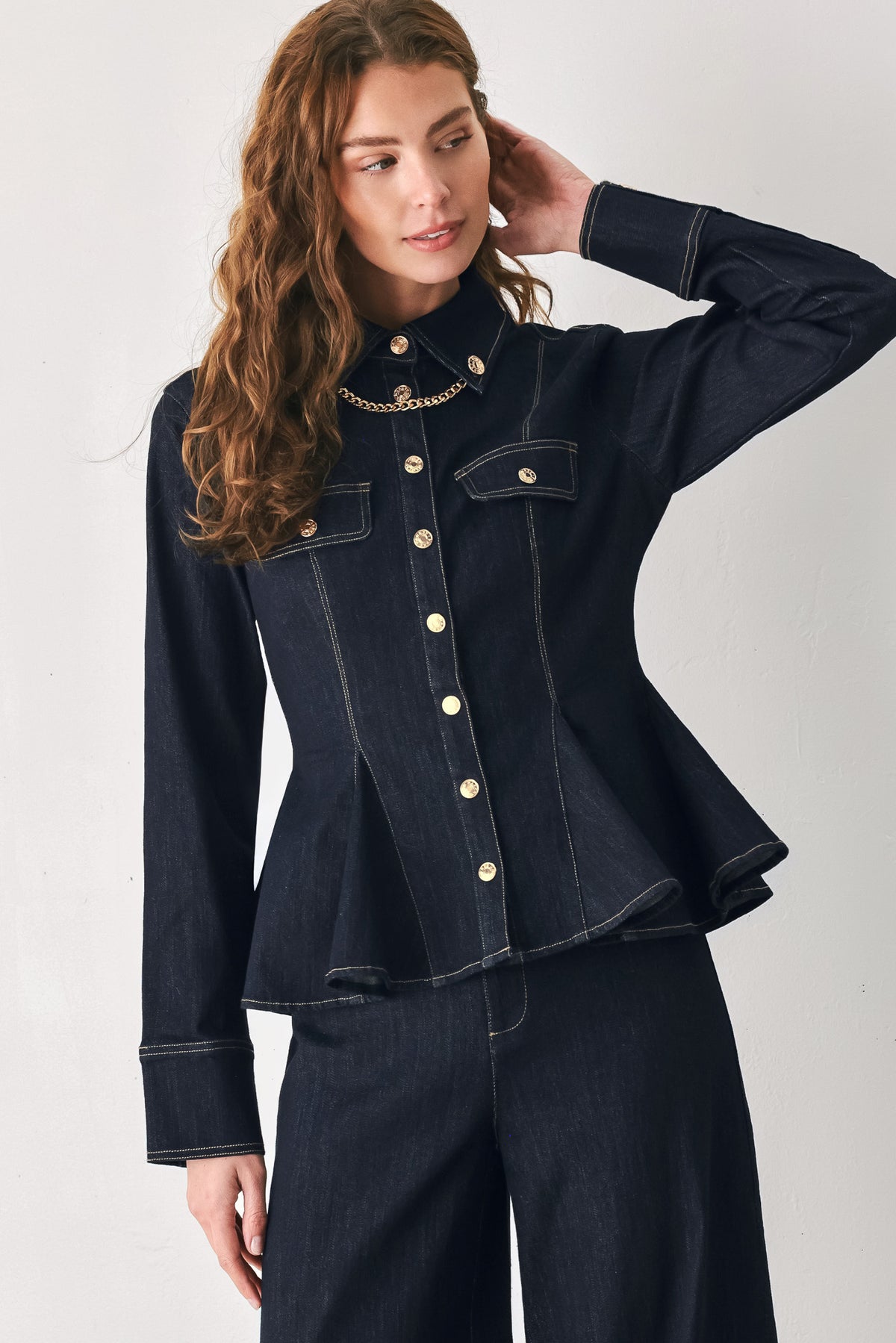 Woman wearing a navy blue denim long sleep button up top with a peplum waist, a collar and chain connected to the corners of the collar | FREEMARKET